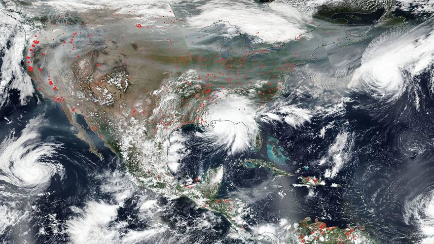 NASA's Aqua satellite captured this true-color image of the United States on Sep. 15, 2020, showing the fires in the West, the smoke from those fires drifting over the country, several hurricanes converging from different angles, and Hurricane Sally making landfall. Red points in the west note areas that are significantly higher in temperature than the areas around it and are indicative of fires. Image courtesy of NASA Worldview, Earth Observing System Data and Information System (EOSDIS).