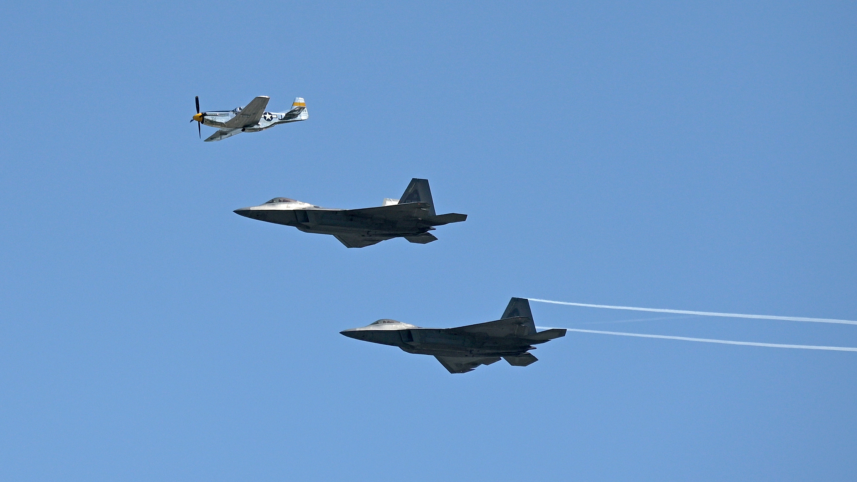 A P-51 Mustang flies in formation with a pair of F-22 Raptors during the Sun ‘n Fun Aerospace Expo. Photo by Phelan M. Ebenhack.
