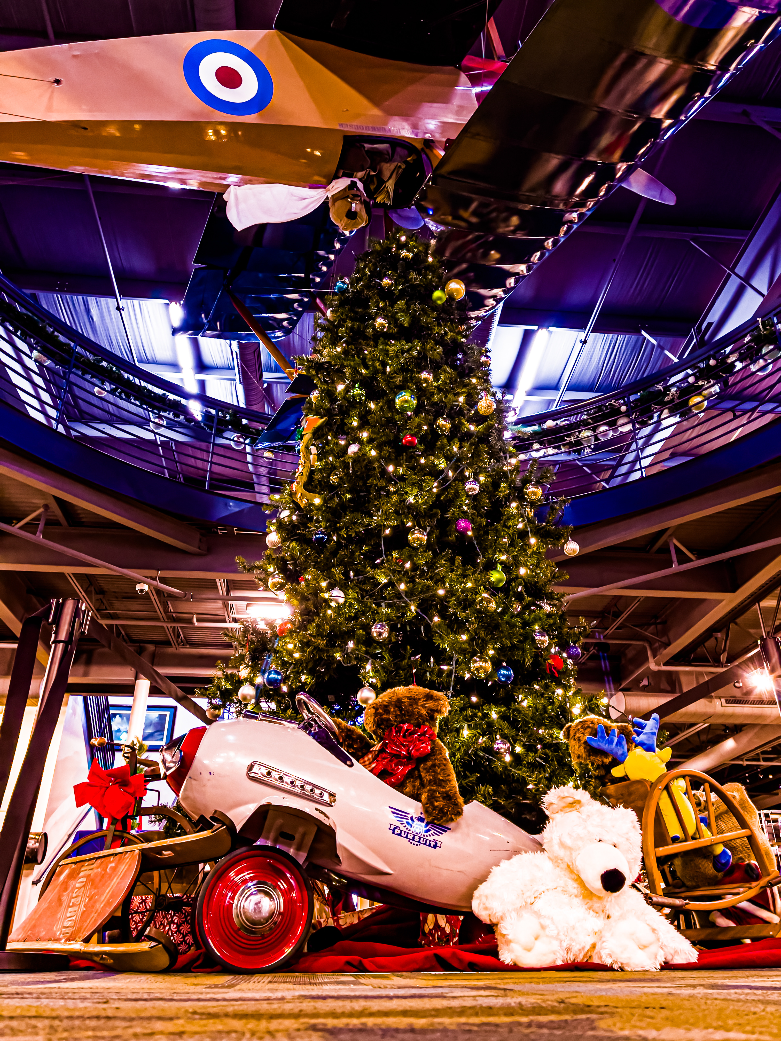 A twinkling Christmas tree is displayed alongside holiday toys and a pilot teddy bear ready to take flight in his silver airplane at the Military Aviation Museum in Virginia Beach, Virginia. Photo courtesy of Zachary Baughman, Military Aviation Museum. 