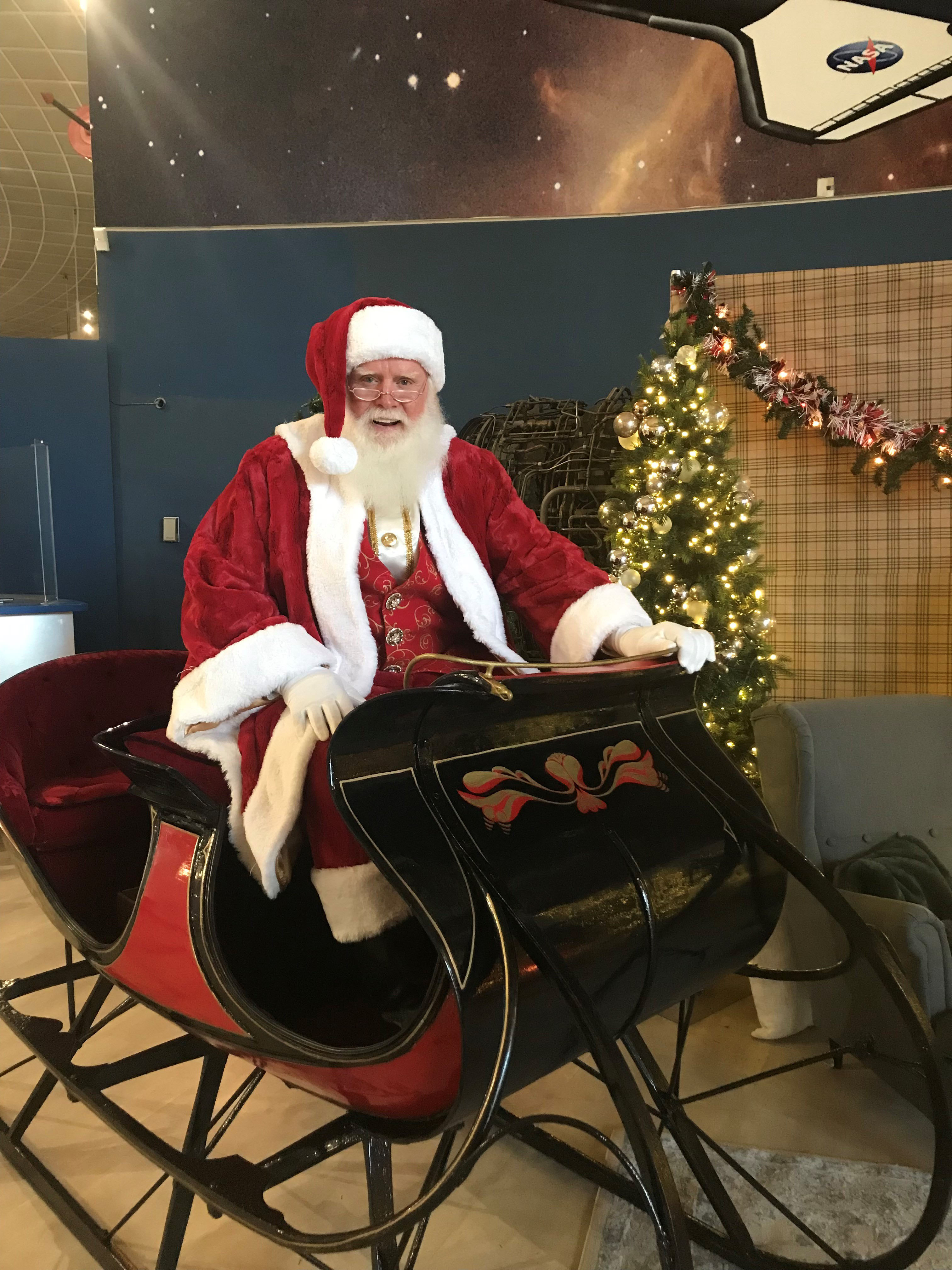 Santa Claus himself poses in his original, recently restored sleigh, “Santa One,” at the San Diego Air and Space Museum.  Photo courtesy of the San Diego Air and Space Museum.