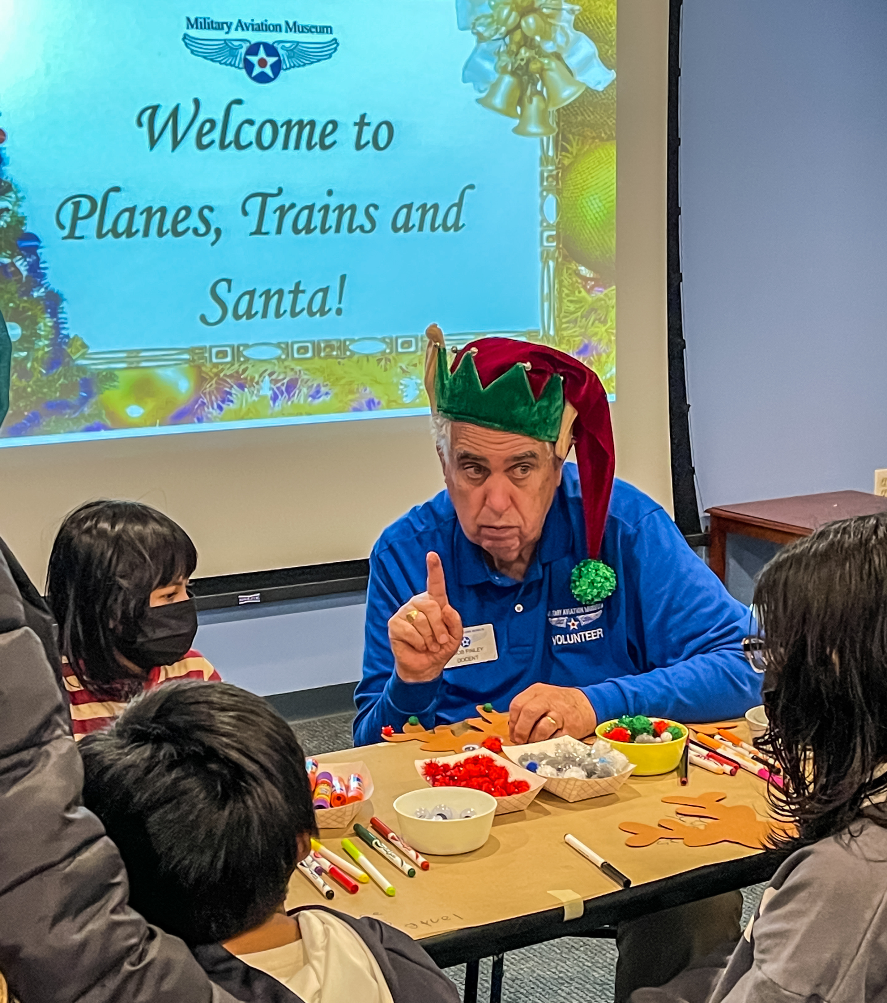 Military Aviation Museum volunteer Bob Finley brings the holiday cheer to families at Planes, Trains and Santa! Photo courtesy of Zachary Baughman, Military Aviation Museum.    