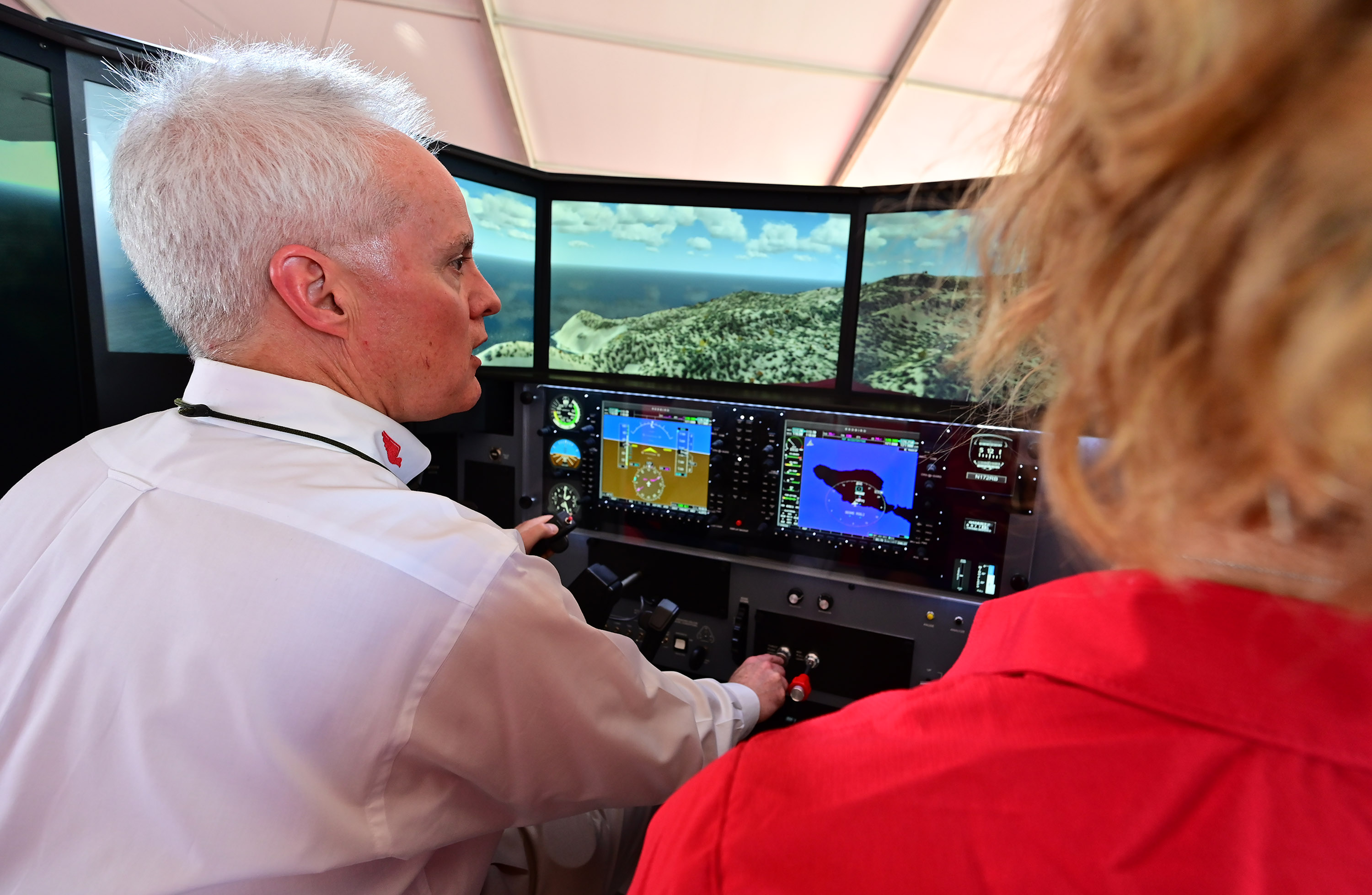 Redbird Flight Simulations Inc. CEO Todd Willinger and CFI Nicole Cunningham demonstrate the new Redbird Pro simulator that uses artificial intelligence to create a customized proficiency plan based on an individual pilot’s input. Photo by David Tulis.