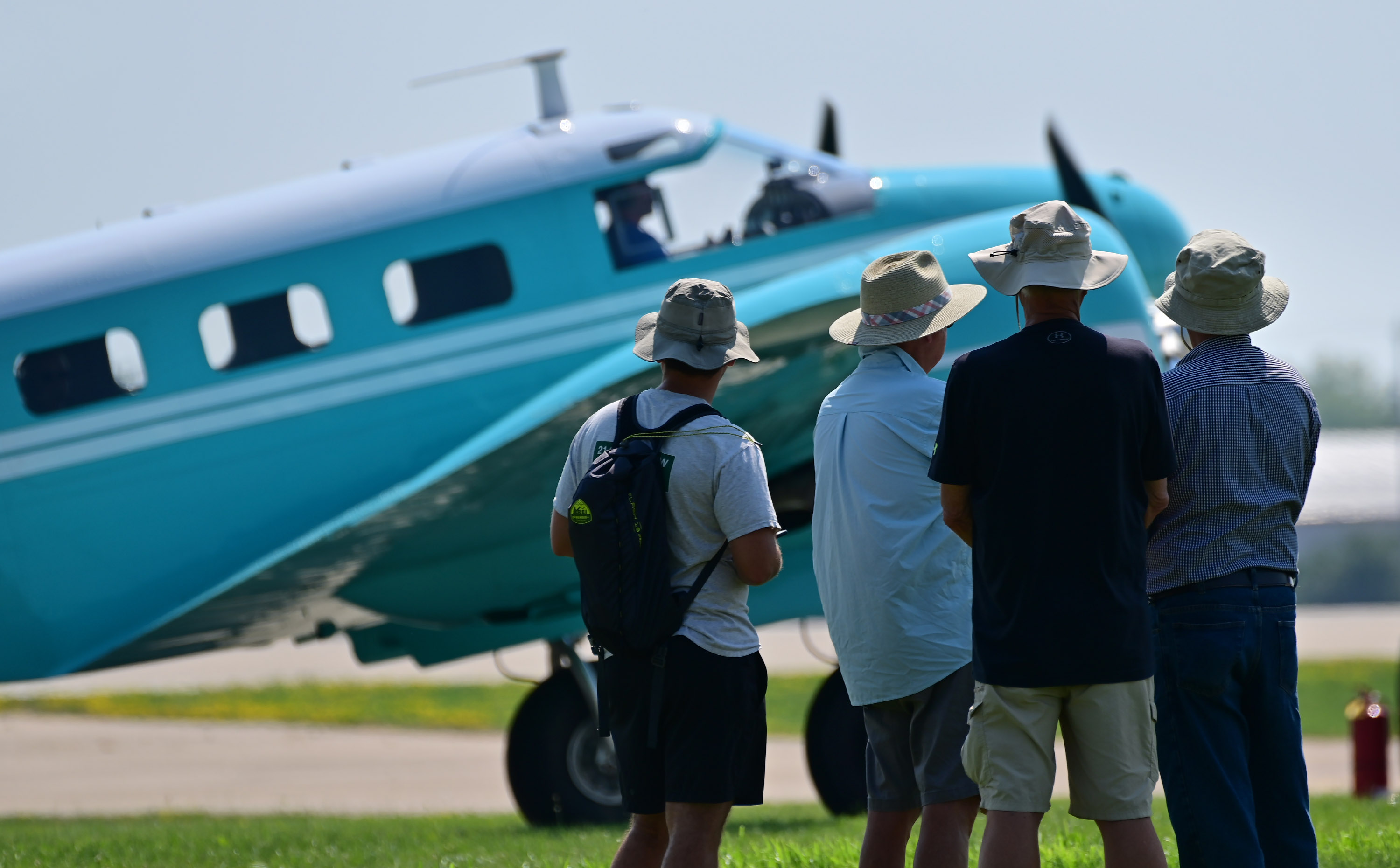 Aviation enthusiasts view a baby blue Beechcraft Model 18 arriving for EAA AirVenture. Photo by David Tulis.
