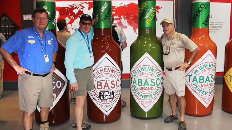 The Tabasco factory tour features a row of giant Tabasco bottles representing seven of the eight flavors now available.  The latest Sriracha flavor is not shown. Pictured left to right: Dave Lewis, owner of Cubs, Floats and Fun; Steve McCaughey, executive director of the Seaplane Pilots Association; and Lyle Panepinto, president of Southern Seaplane Inc. Photo by Mark Twombly. 
