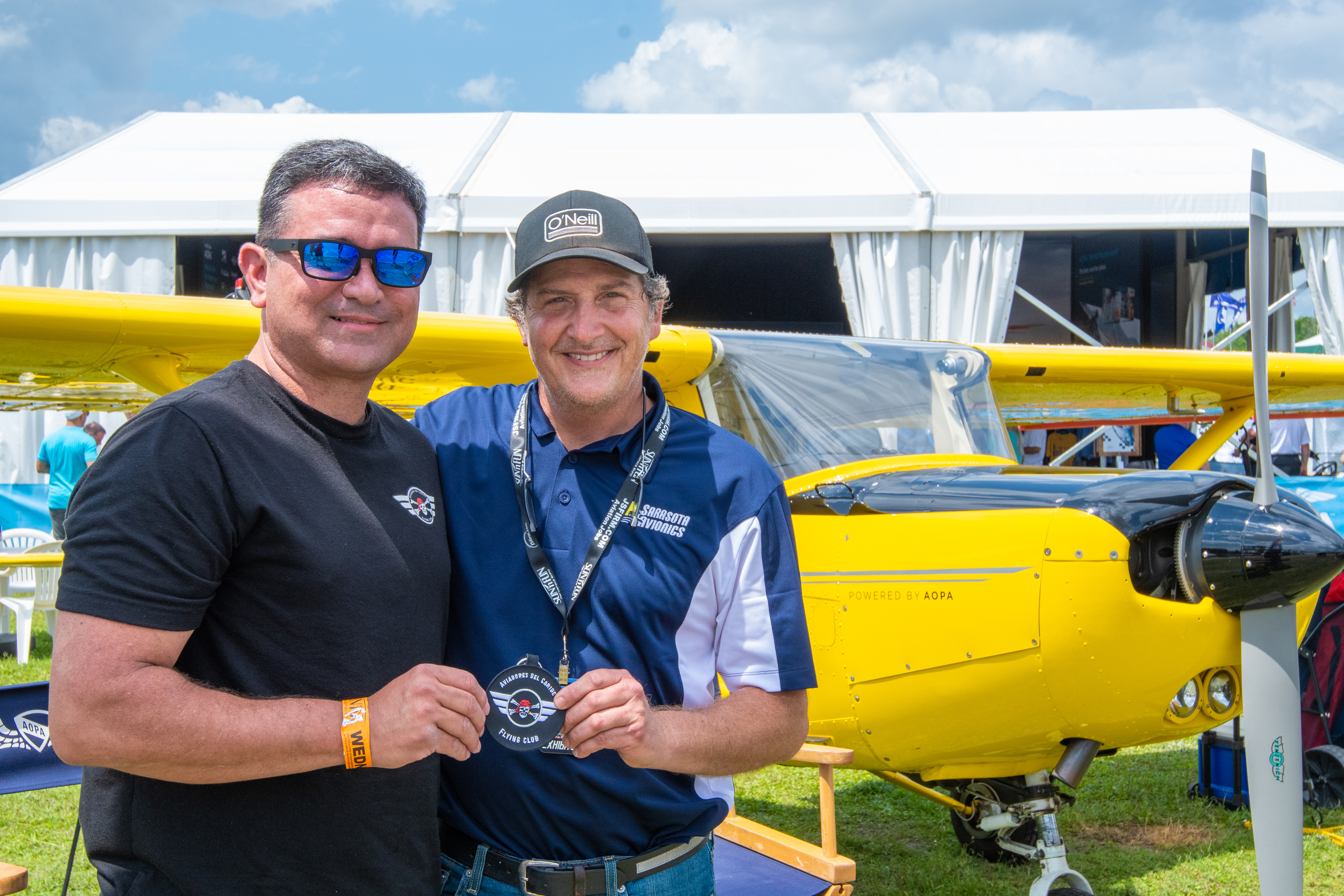 René Asencio and Gilbert Perez show off an Aviadores Del Caribe patch in front of AOPA's You Can Fly Cessna 150.  Photo by Niki Britton.