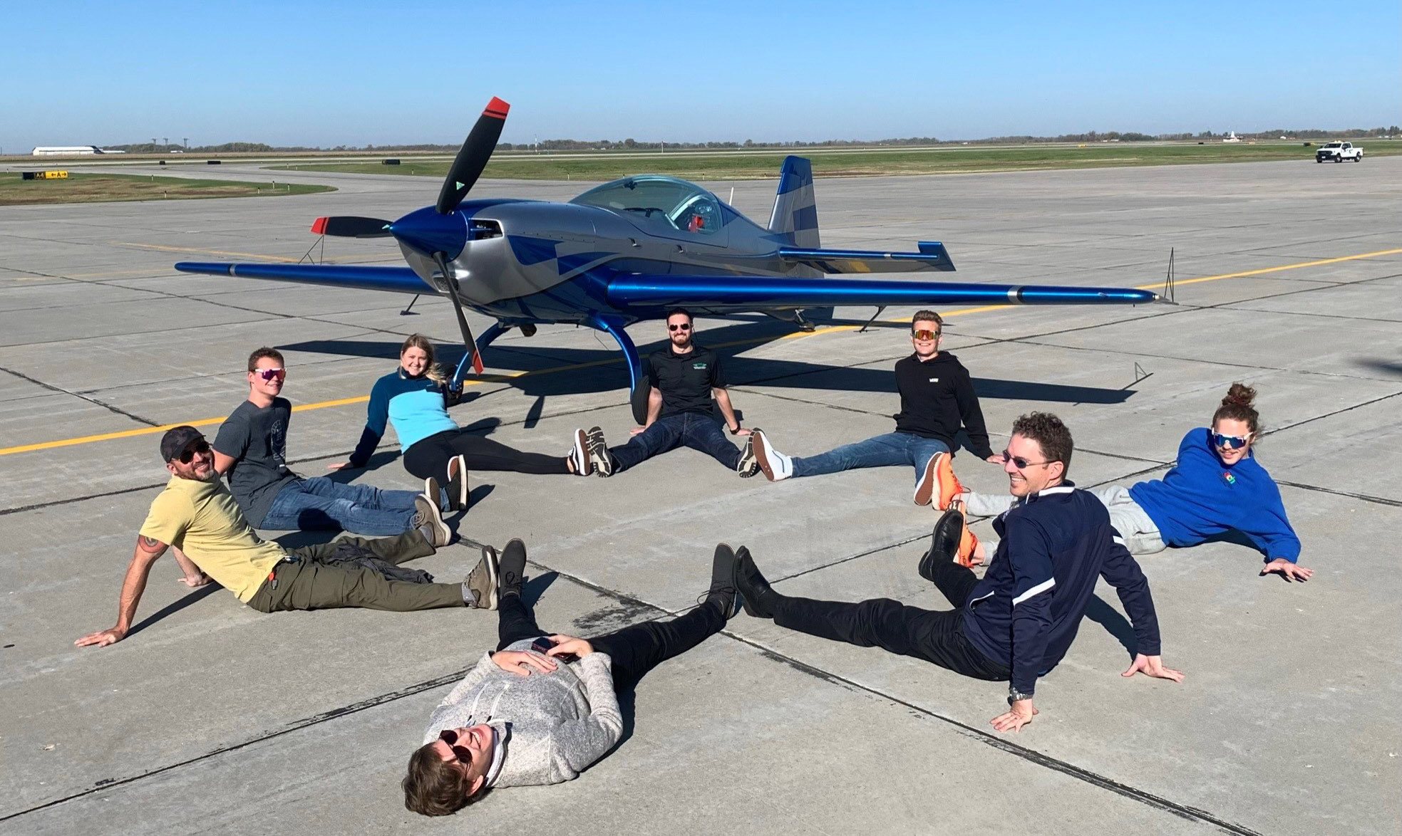Clockwise from far left: Pilot Shaun Brautigan and University of North Dakota aviation students Shawn Higgins, Mikaila Gillis, Jon DeLone, Christoph Webber, Andrew Coughlin, Mike Lents, and Ben Stassen sit in front of the Extra NG during Brautigan and Angela Rogers' cross-country flight. Photo courtesy of Shaun Brautigan. Clockwise from far left: Pilot Shaun Brautigan and University of North Dakota aviation students Shawn Higgins, Mikaila Gillis, Jon DeLone, Christoph Webber, Andrew Coughlin, Mike Lents, and Ben Stassen sit in front of the Extra NG during Brautigan and Angela Rogers' cross-country flight. Photo courtesy of Shaun Brautigan.