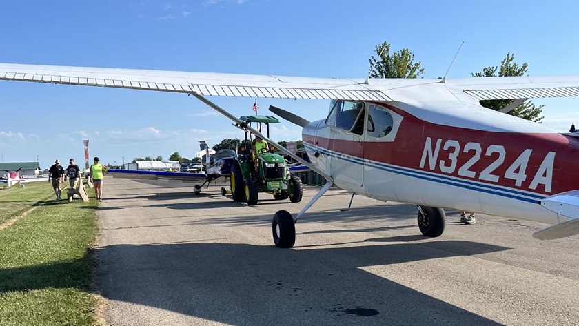 The 2023 AOPA Sweepstakes Cessna 170 and the 2022 AOPA Sweepstakes Grumman Tiger being are towed to Booth 463 at AirVenture. Photo by Erick Webb.
