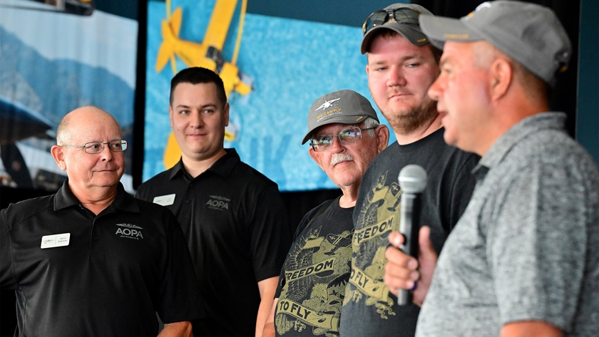 (left to right) AOPA Flying Clubs Initiative Director Steve Bateman and Flying Clubs Initiative Manager Drew Myers recognize Al Gerhold, Paul Adams, and Scott Jefson of the Lake Shelbyville Flying Club, the 200th AOPA You Can Fly flying club, during the Pilot Town Hall at EAA AirVenture Oshkosh July 28. Photo by David Tulis. 