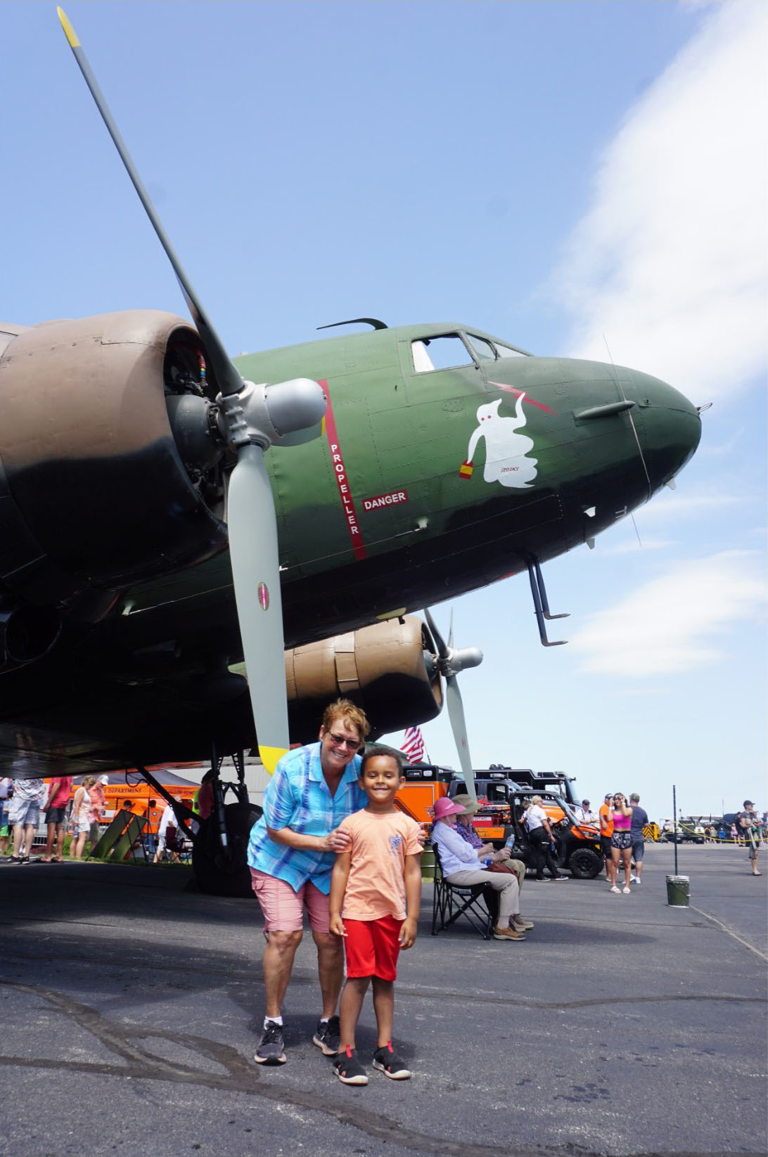 Marilee Hartman poses with her grandson underneath of Spooky, a C–47 from Kansas. Hartman's father trained Hellcat mechanics during World War II. Photo by Cayla McLeod Hunt.