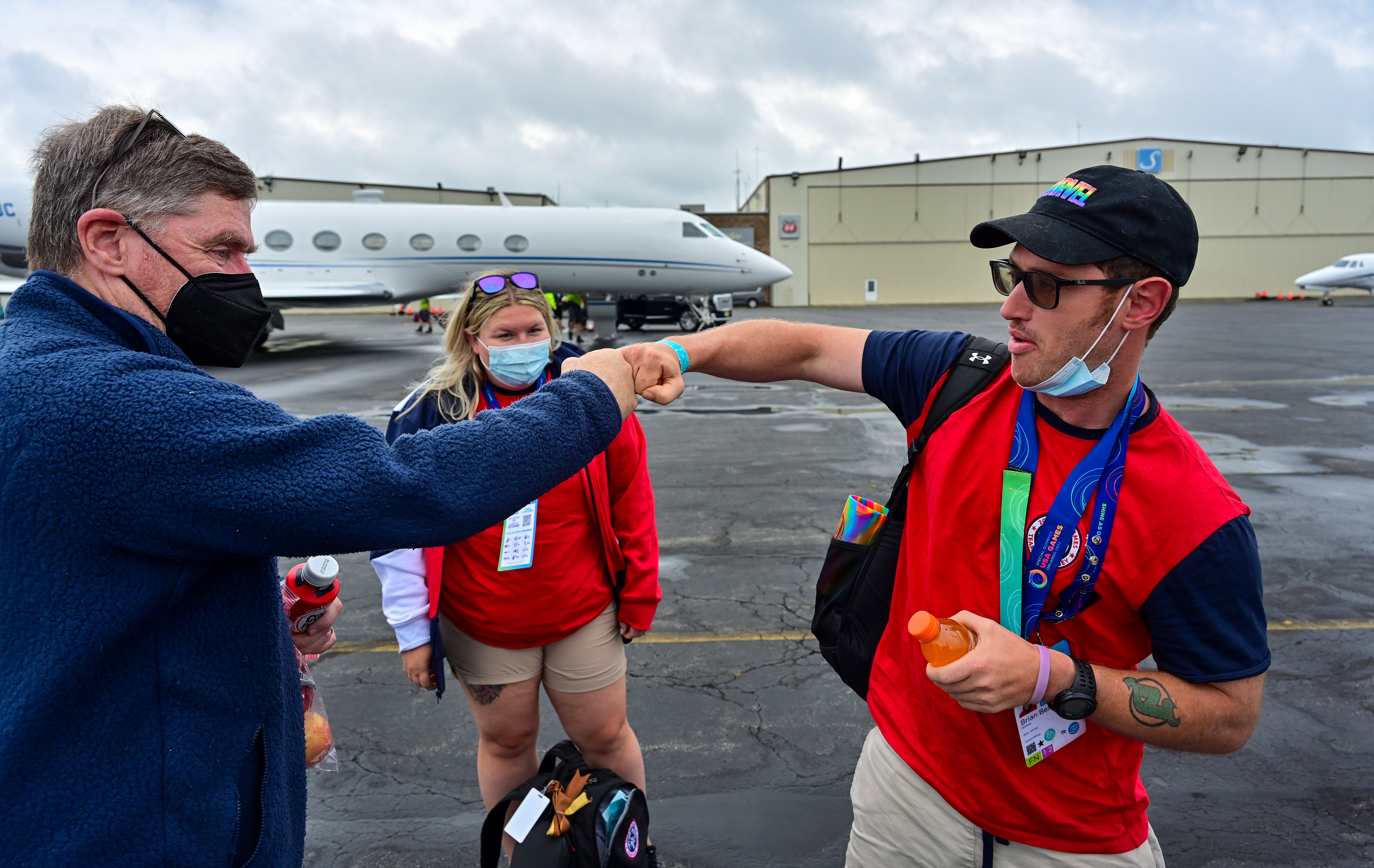 Gold medal-winning Special Olympian Brian Beirne, a powerlifter, fist-bumps his father, John, at Trenton Mercer Airport in New Jersey after flying from Orlando Executive Airport during the Textron Aviation-sponsored Special Olympics Airlift following the Special Olympics USA Games in Orlando, Florida, June 12, 2022. Coach Amanda Bendorf, who also flew in the airlift, watches. Photo by David Tulis.