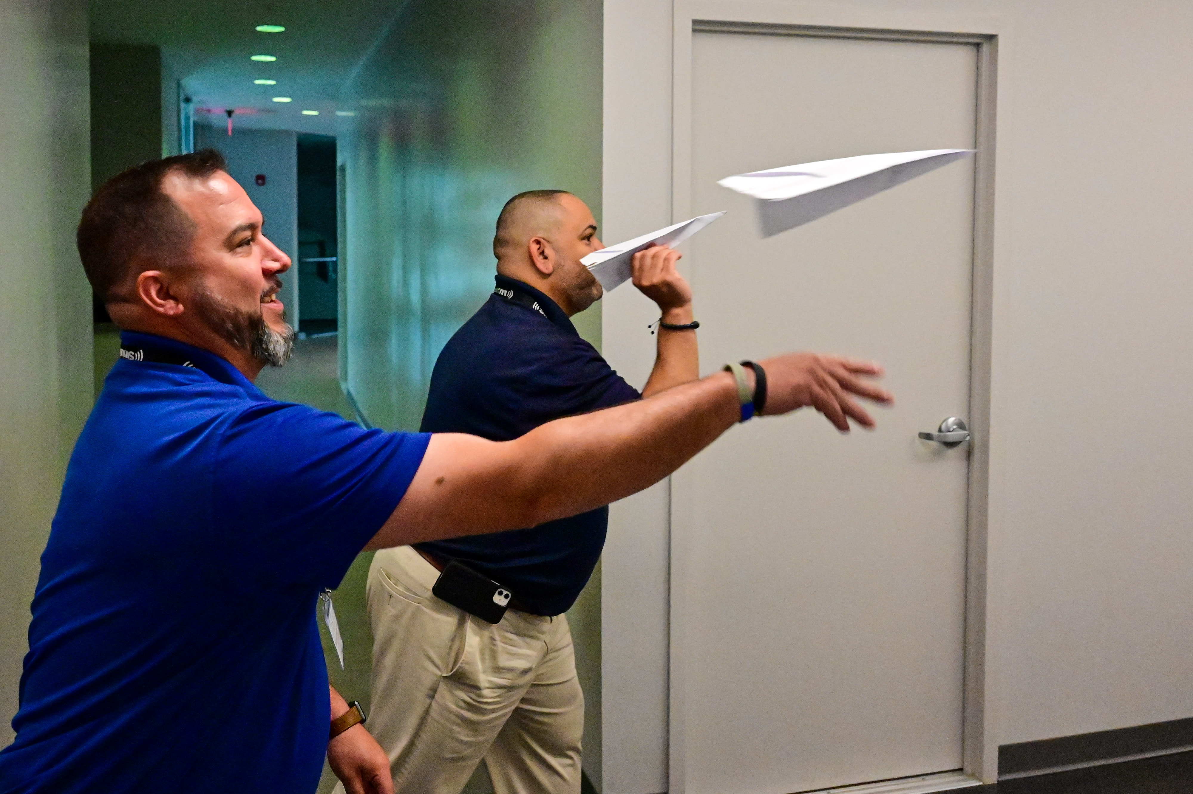 High school educators Richard Roughton, left, and Raymond Gonzalez, both from New York, fly paper airplanes during an interactive exercise. Photo by David Tulis. 