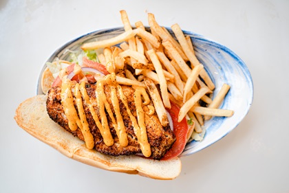 A freshly caught grouper po’boy, served fully loaded with fries, is delivered to the author’s table at The Hangout. Photo courtesy of Tyler Bradfield. 