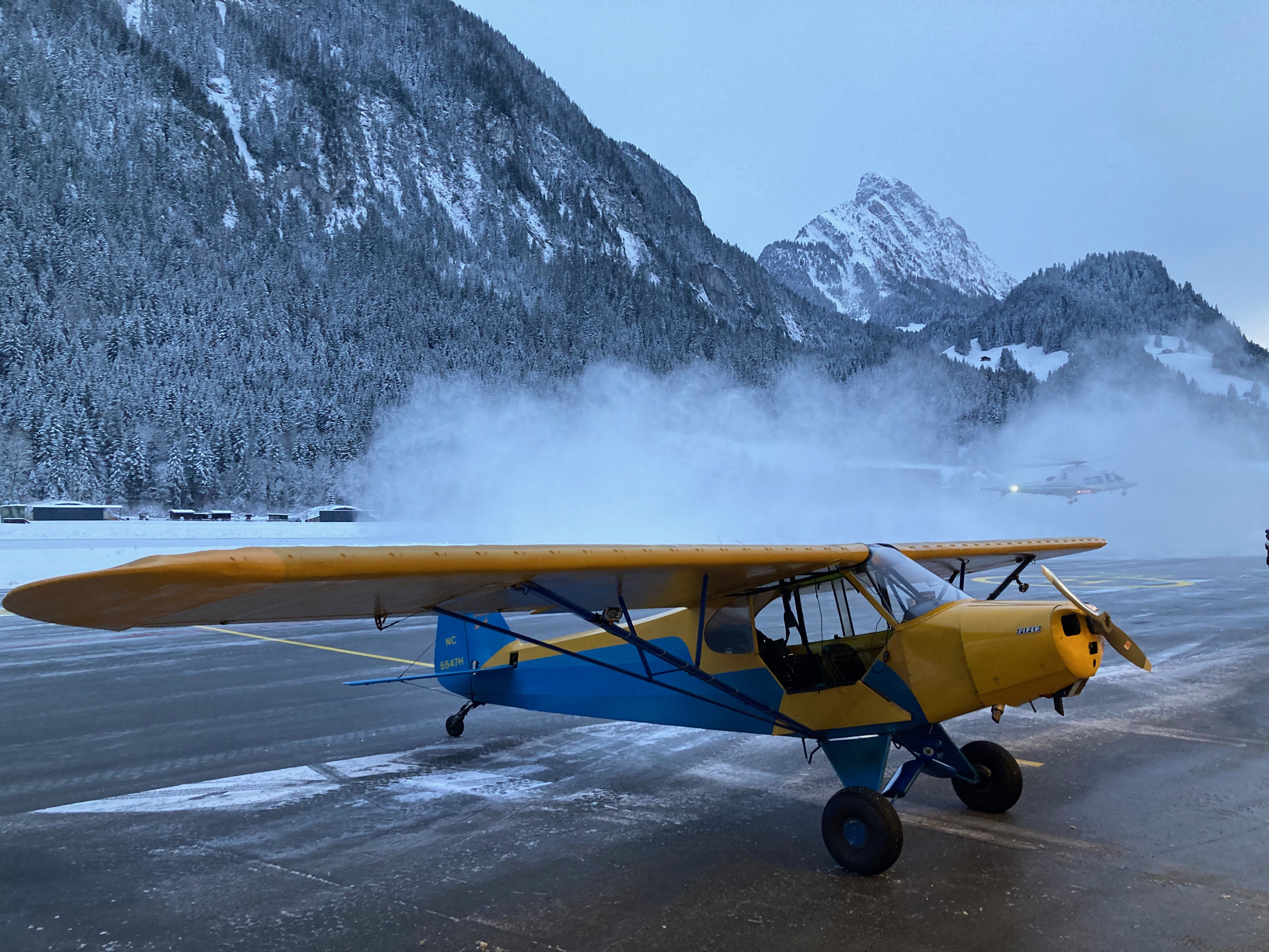 A helicopter kicks up snow behind the author's airplane in Gstaad, Switzerland. Photo by Garrett Fisher.