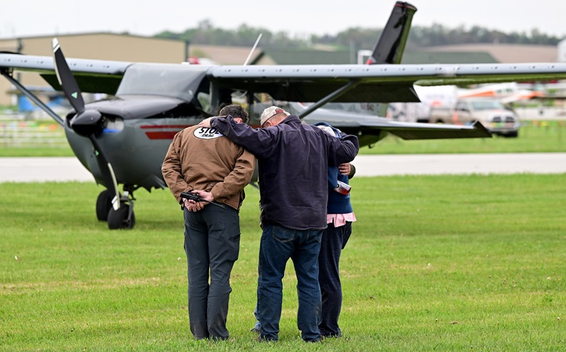 Spectators gather to pray after watching competitor Tom Dafoe die in an apparent stall-spin crash at the MayDay STOL event in Nebraska May 20. Photo by David Tulis.