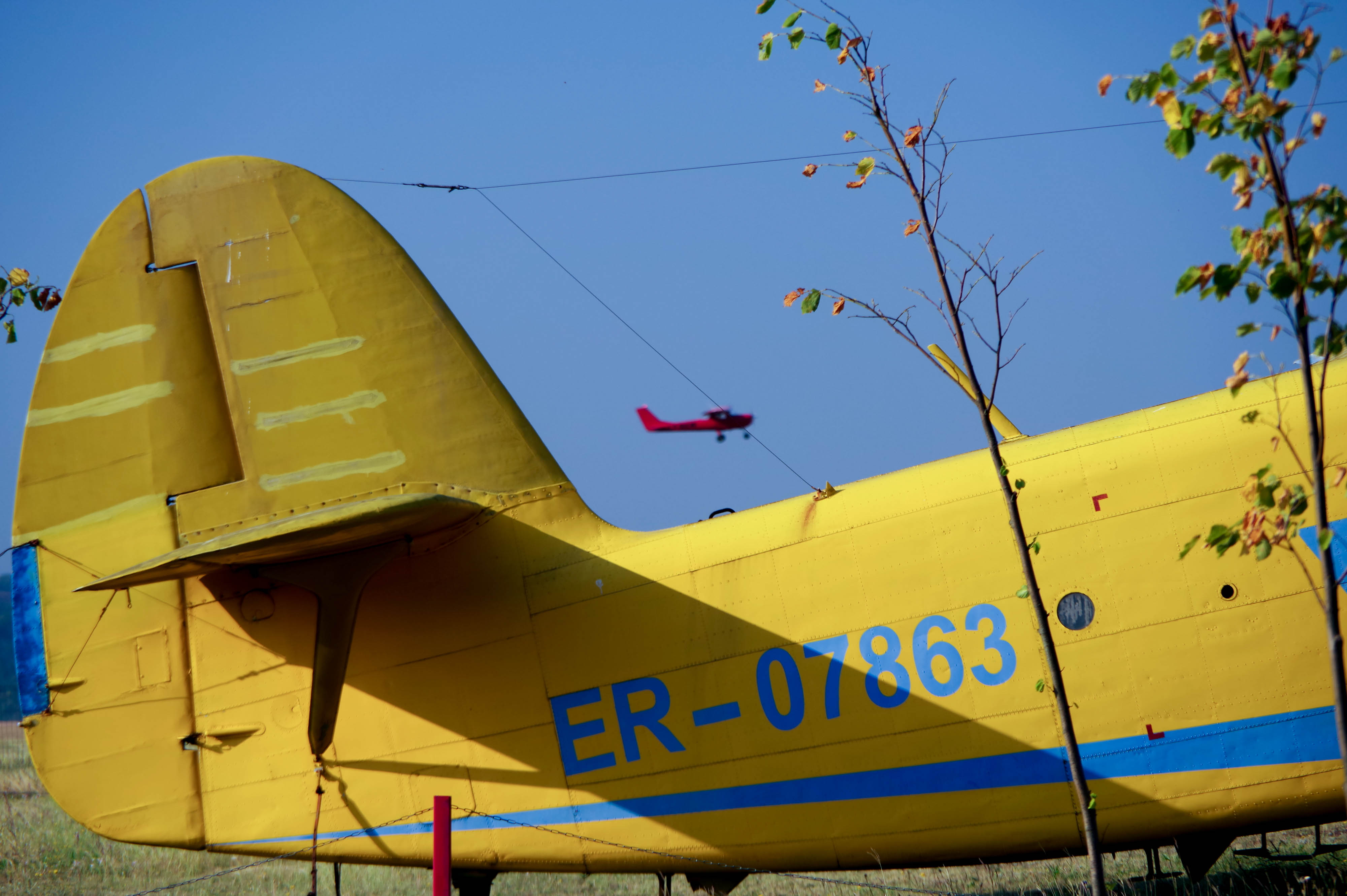 The school's red F150  flies abeam the airfield's showpiece Antonov AN-2.  Photo by Conner Wilson.