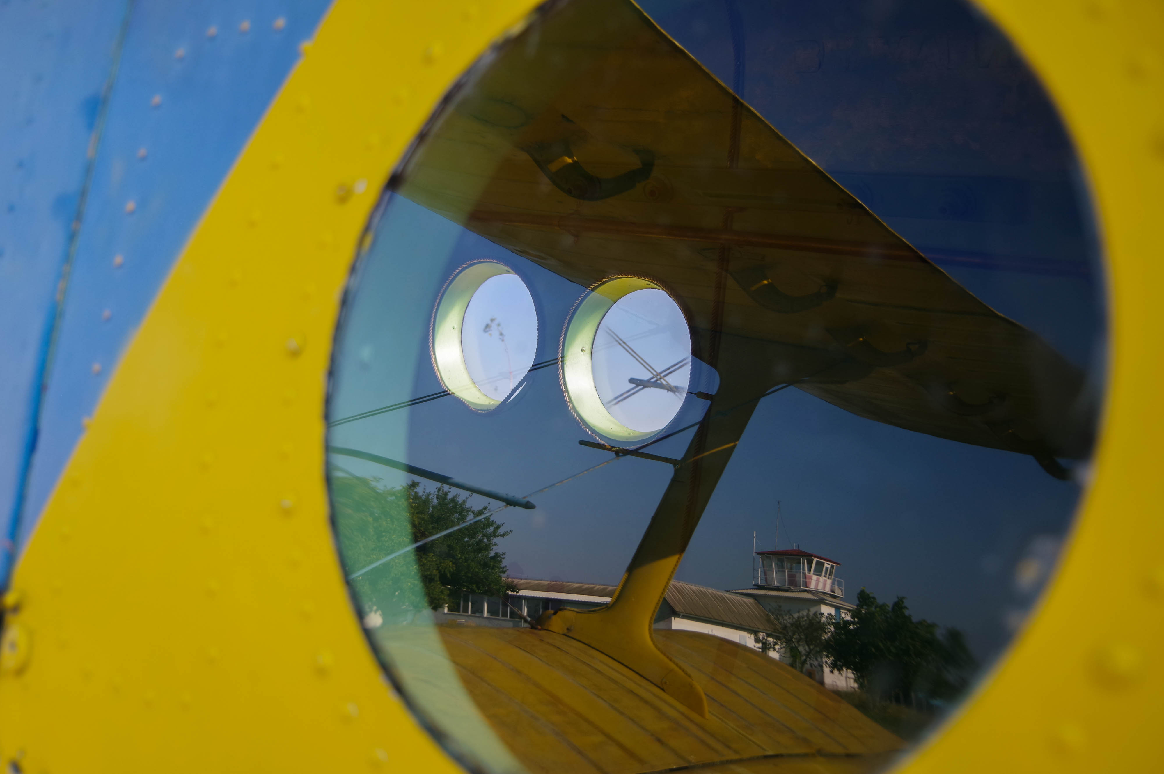 The airfield’s nonoperational tower is reflected in the porthole window of the Antonov AN-2. The tower is usually only operational during airshows, which haven't taken place in over half a decade. Photo by Conner Wilson.