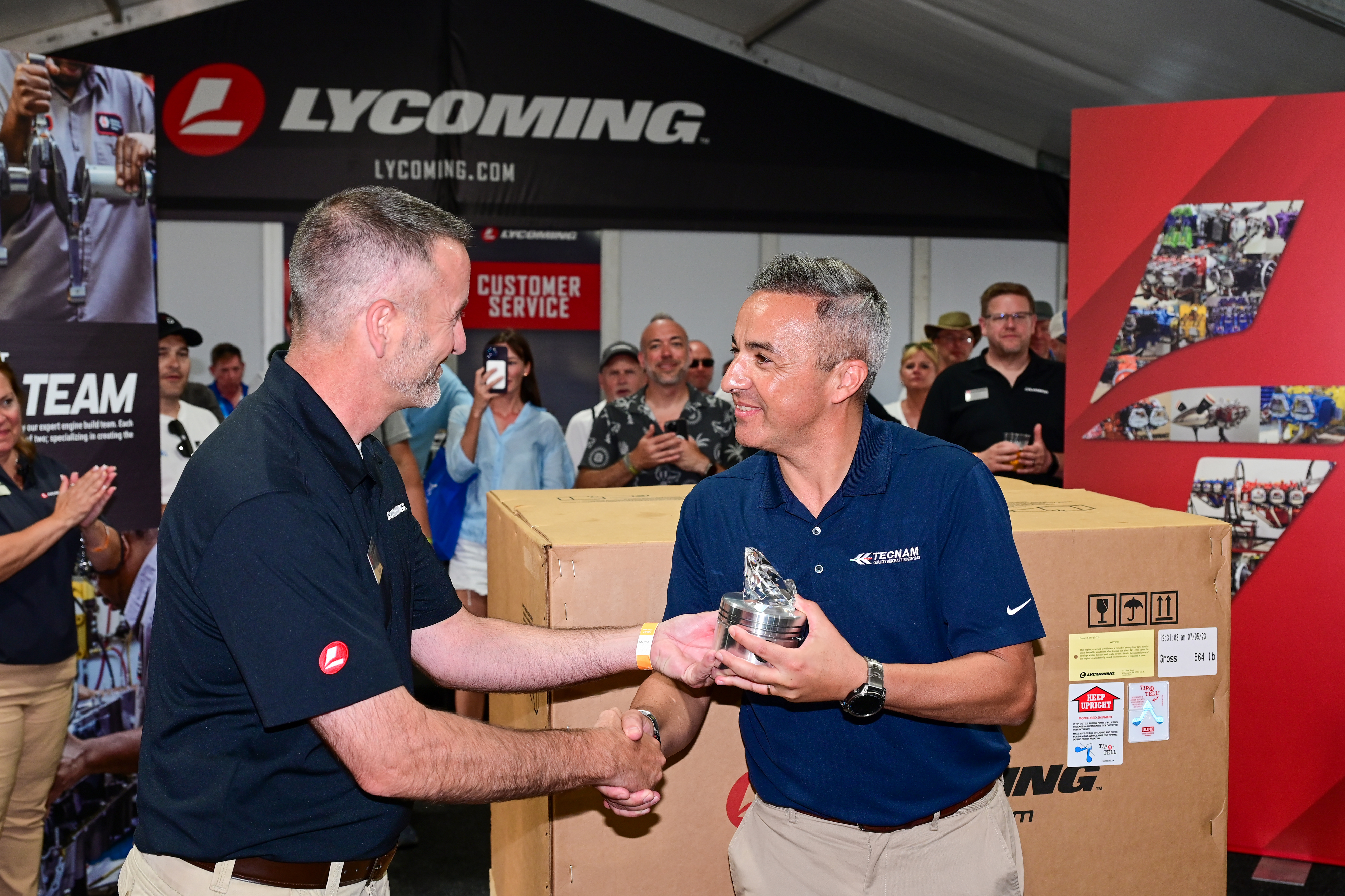 Lycoming's Aaron Spotts presents Tecnam Aircraft's Walter Da Costa recognition for 75 years of aircraft manufacturing during EAA AirVenture. Photo by David Tulis.