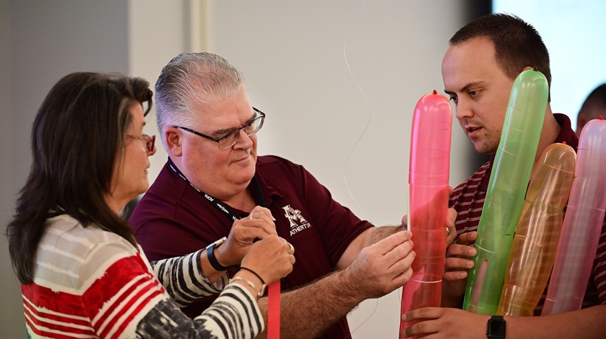 High school educator Alan Williams helps his teammates Carla Ladner and Chris Eckler wrap four balloons together to simulate a rocket payload during an AOPA teacher training event in 2019. Photo by David Tulis.