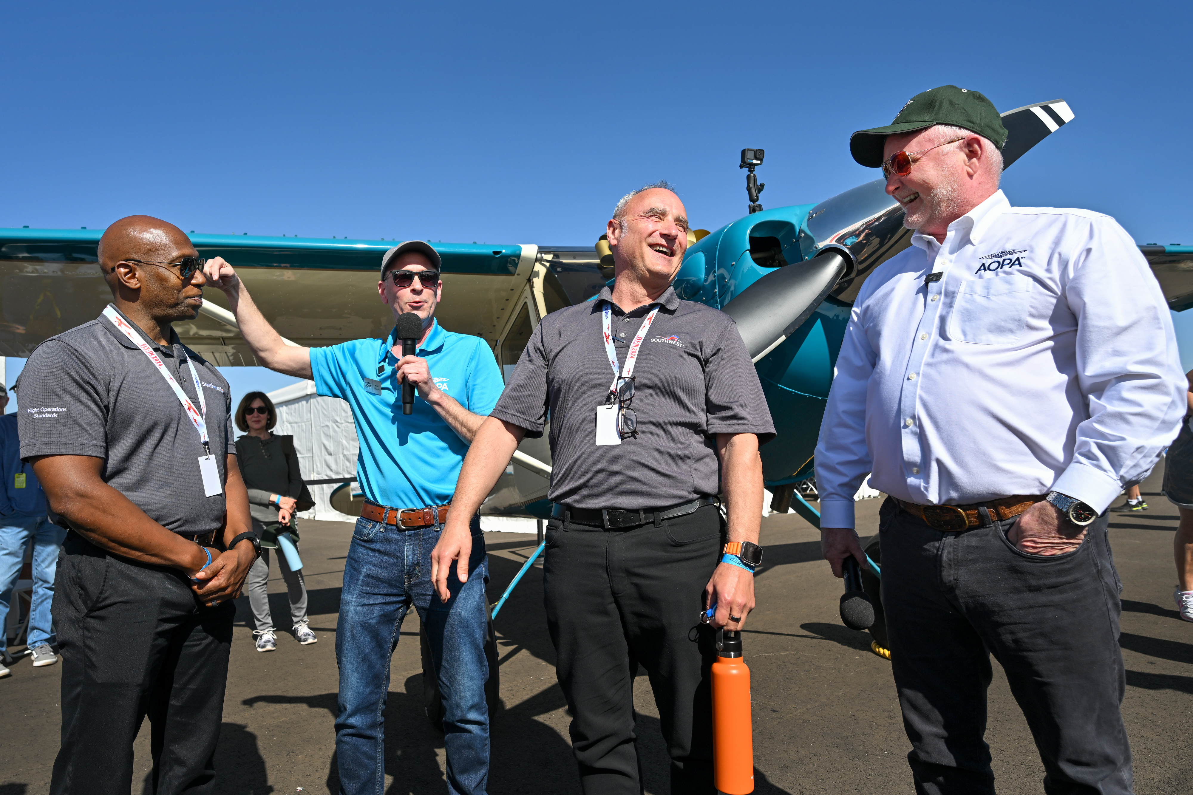 Southwest Airlines pilot Cliff Gurske takes in the news from AOPA President Mark Baker and Media and Marketing Vice President Kollin Stagnito, with Southwest colleague and Assistant Chief Pilot Mel Meadows, who was in on the giveaway ruse, as he is announced the AOPA Sweepstakes Cessna 170B winner. Photo by David Tulis.