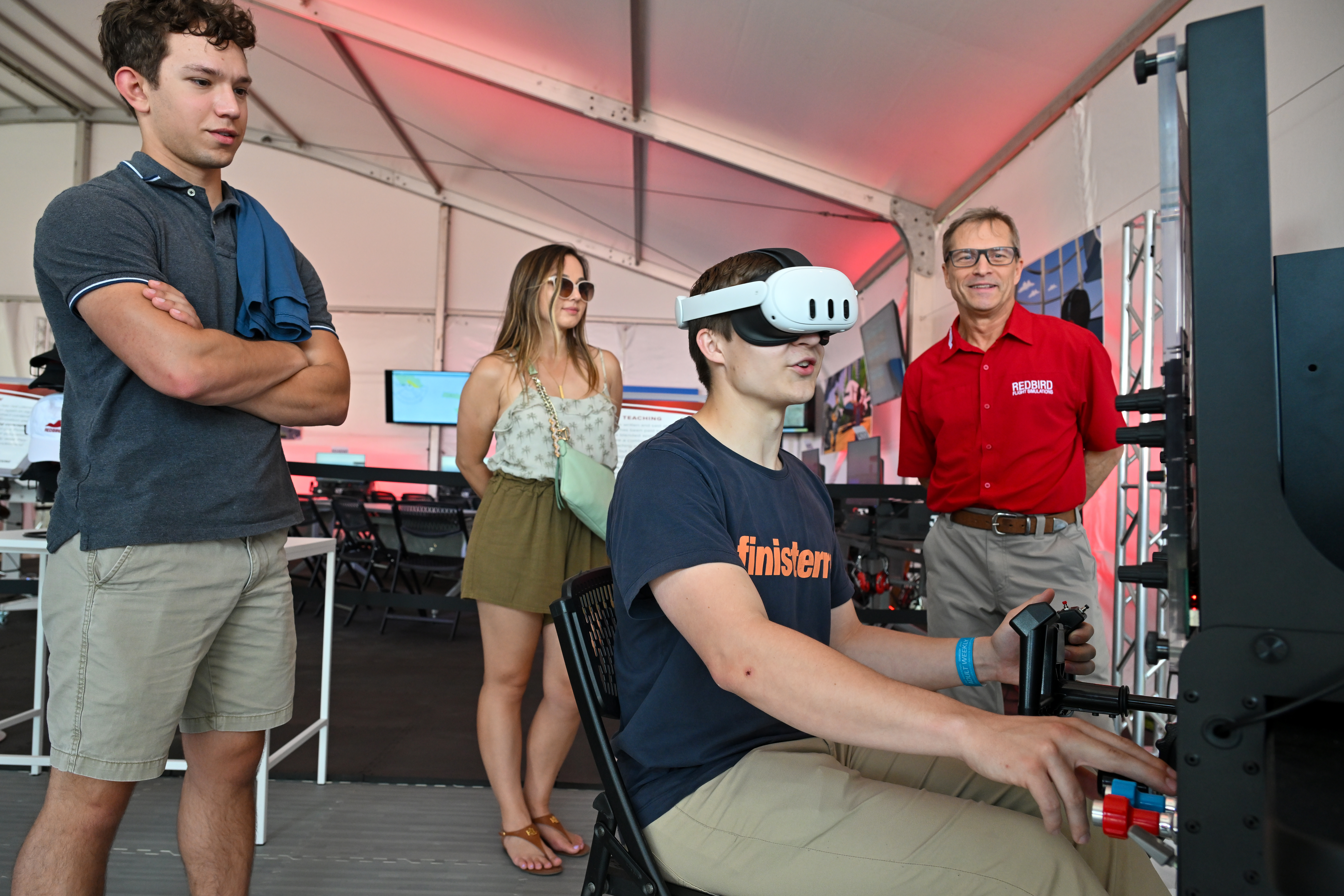 An attendee tries virtual reality goggles at the Redbird Flight Simulations display. Photo by David Tulis.