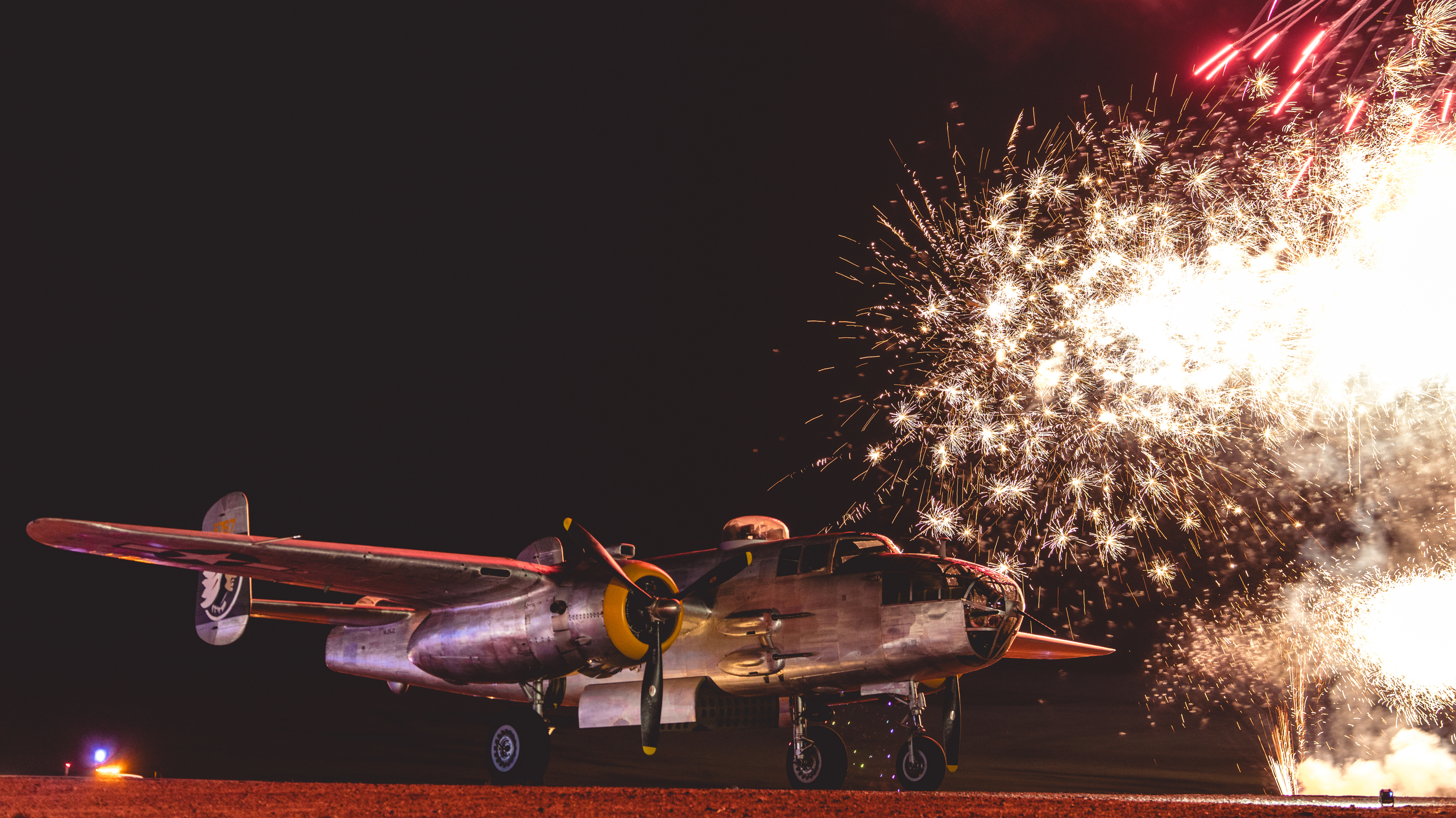 A North American PBJ Mitchell is backlit by fireworks. Photo by Jake Teague.