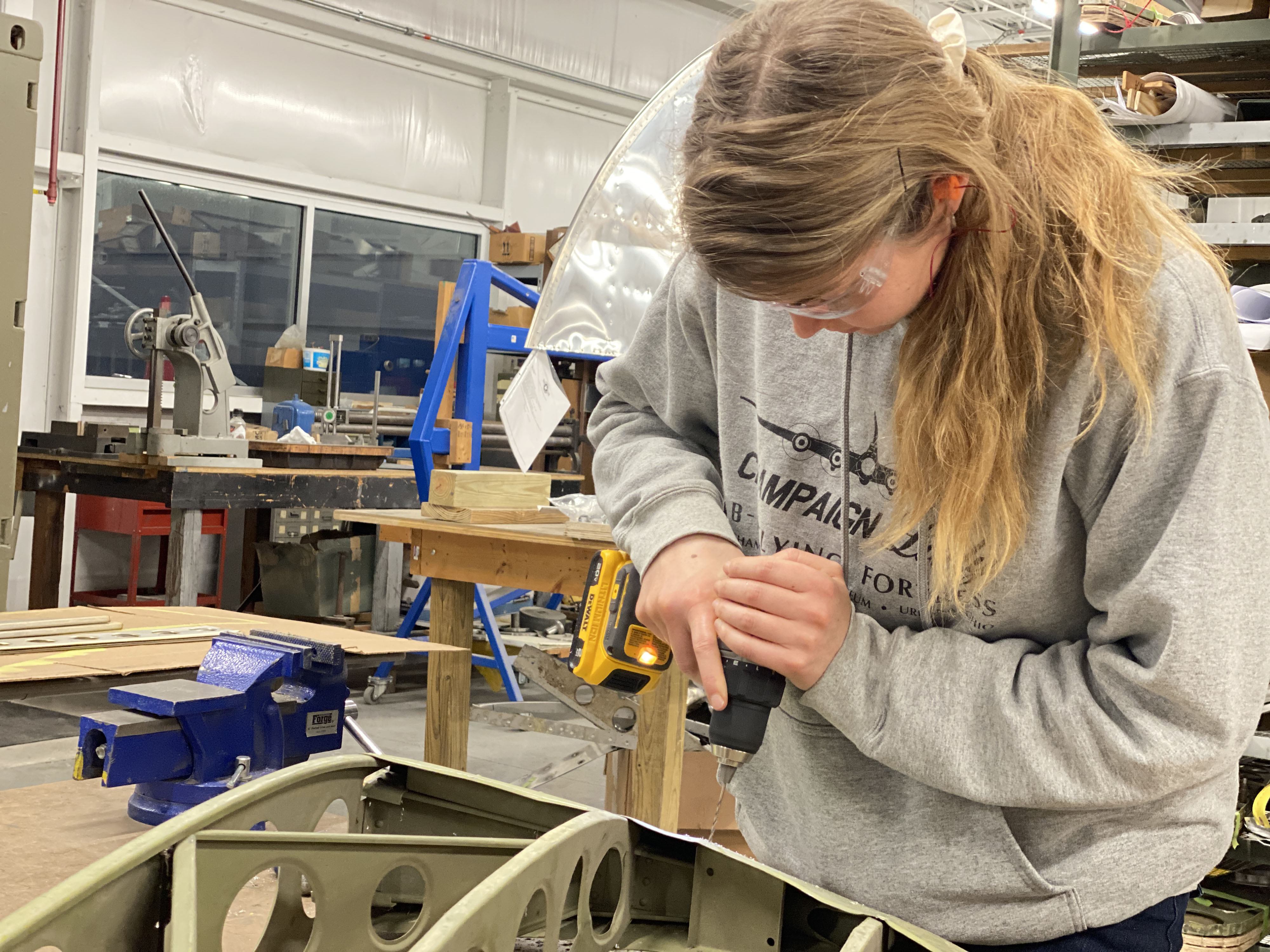 Halee Reddick drills rivets out of a piece of aluminum that she will be repairing. Reddick, a pianist who also paints houses, has a knack for riveting and helped rivet most of the right wing’s outboard side. Photo by Alyssa J. Cobb.