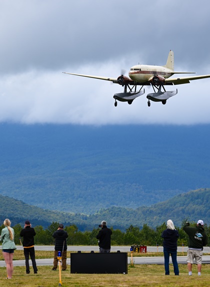A Douglas DC-3 floatplane makes an impromptu flight around Greenville Municipal Airport. The aircraft is equipped with massive EDO floats, Wright radial engines, and three-blade propellers. Photo by David Tulis.