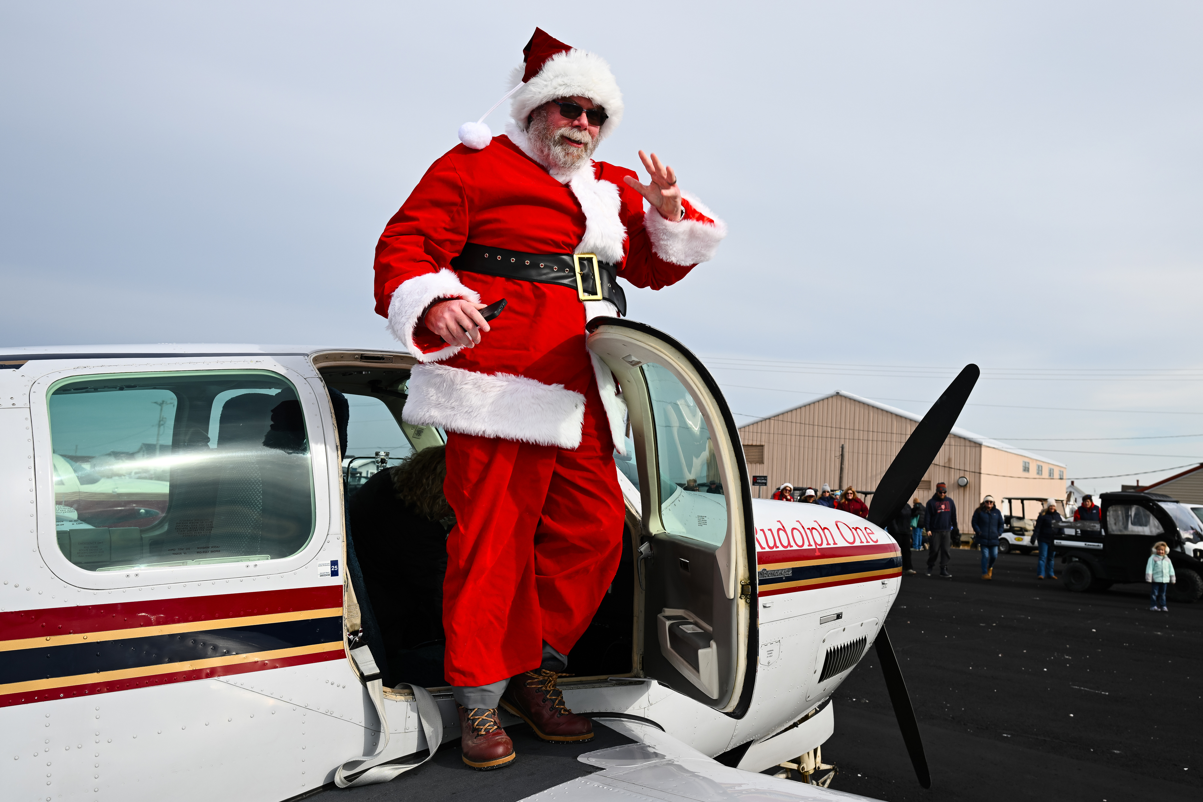Santa Claus (Patrick Lindstrom) exits a Beechcraft Bonanza to deliver candy, holly branches, school supplies, and presents. Photo by David Tulis.