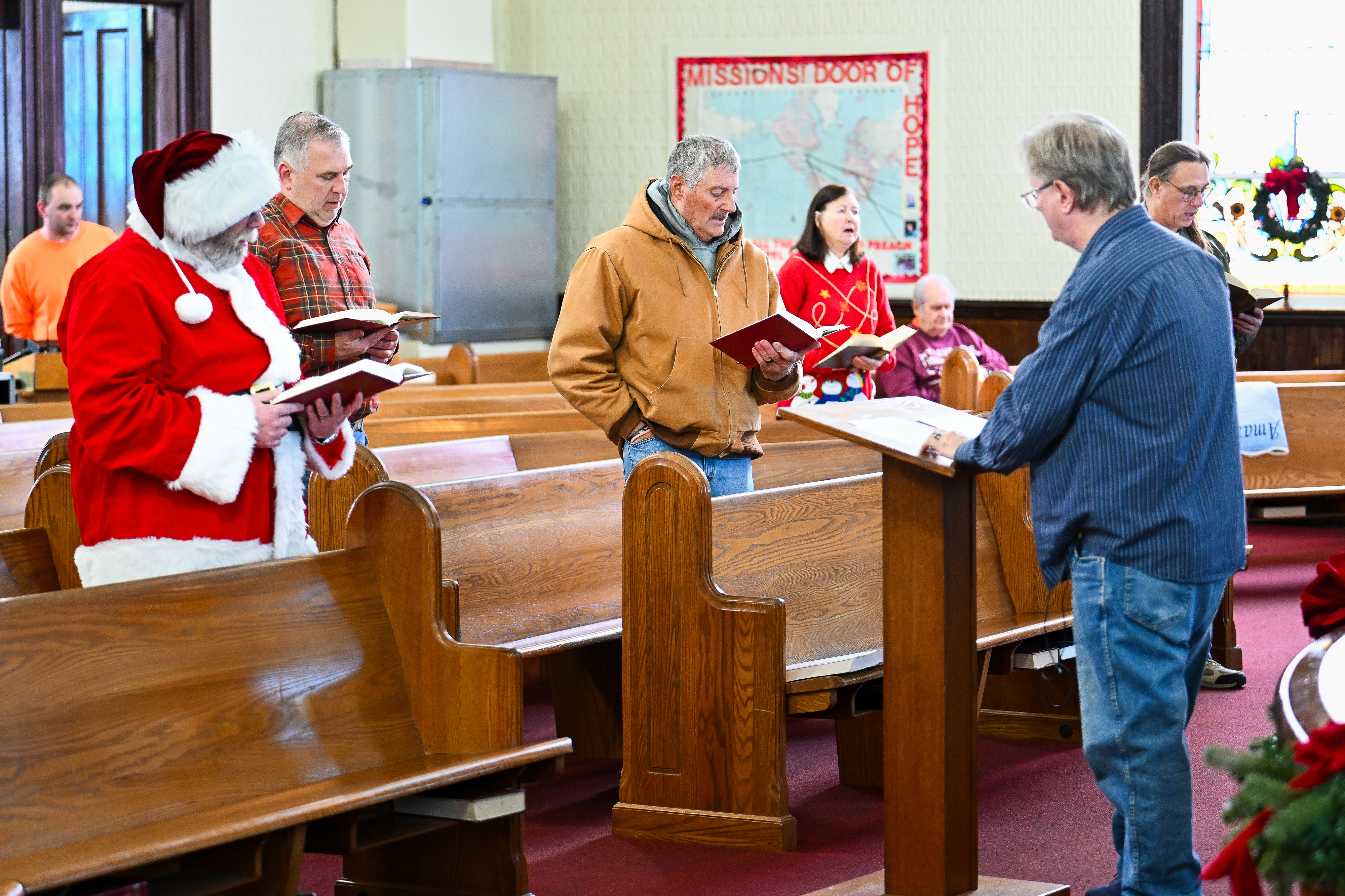 Tangier Island Mayor James ‘Oooker’ Eskridge, center, and Santa Claus Patrick Lindstrom, left, participate in a service at Swain Memorial Methodist Church on Tangier Island, Virginia, December 13. Photo by David Tulis.