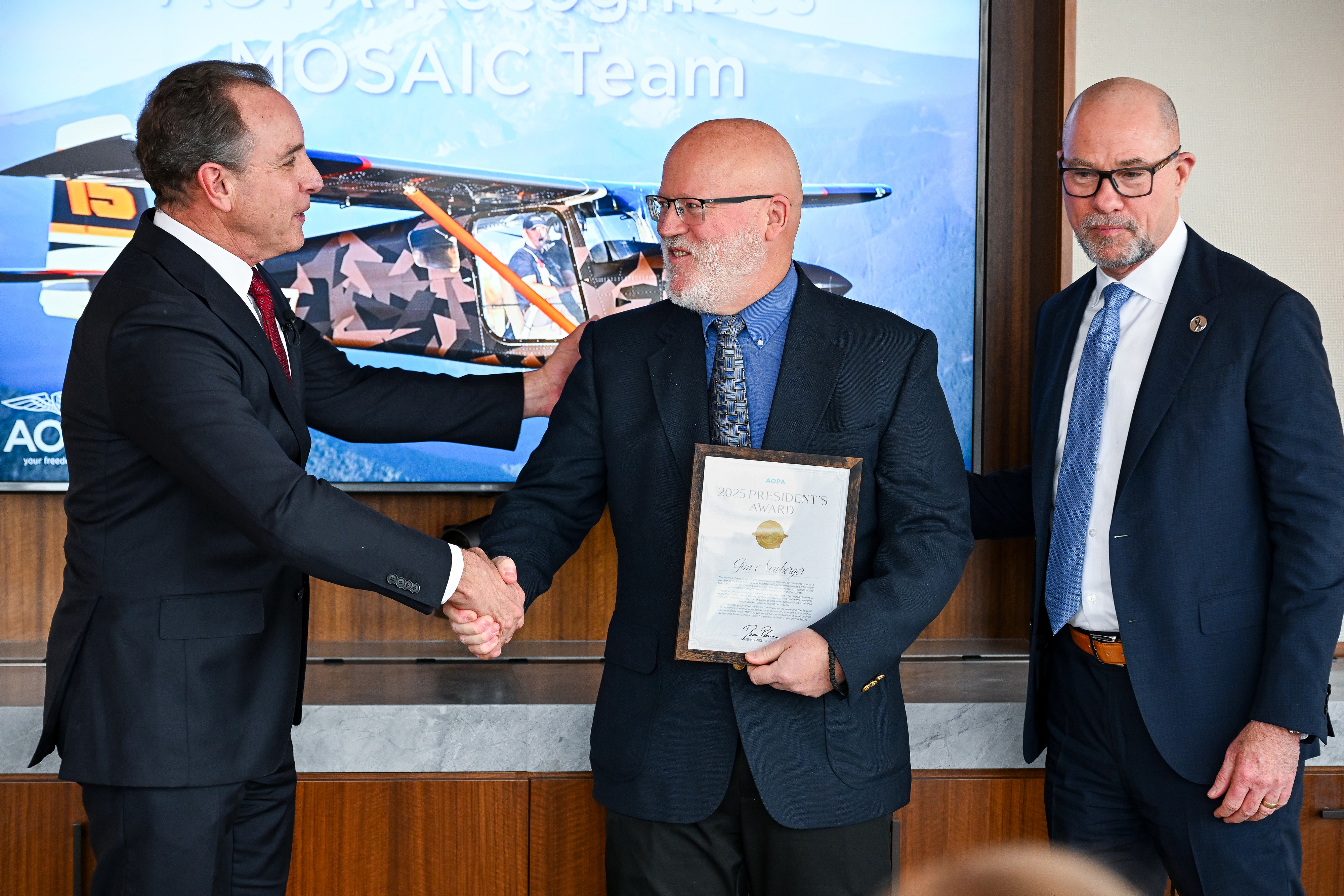 AOPA President Darren Pleasance presents an AOPA President's Award to MOSAIC lead Jim Newberger as FAA Administrator Brian Bedford looks on. Photo by David Tulis.