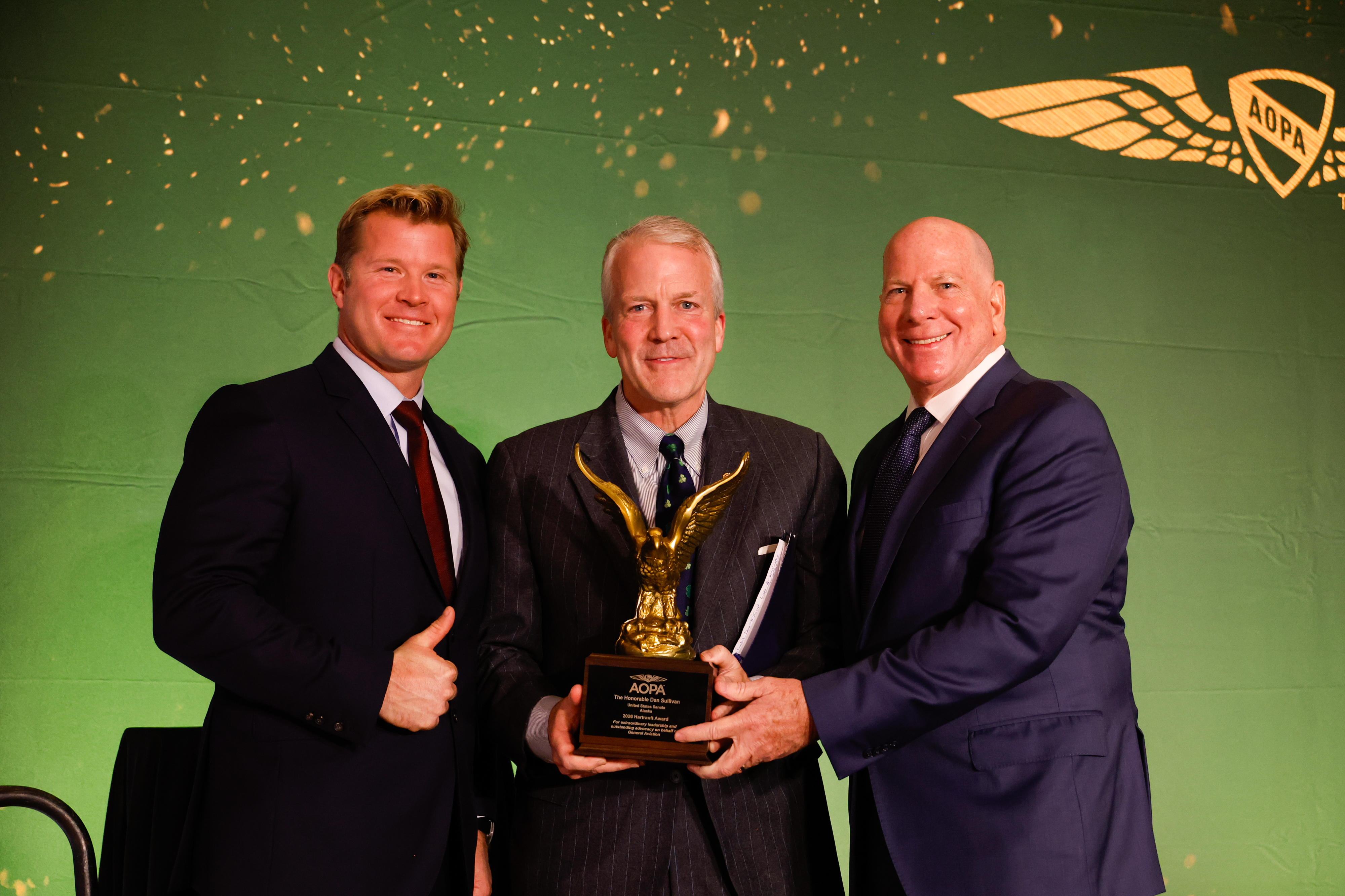 Sen. Tim Sheehy, left, and AOPA Senior Vice President of Government Affairs and Advocacy Jim Coon, right, presented Sen. Dan Sullivan with the Joseph B. “Doc” Hartranft Award. Photo by Chris Rose.