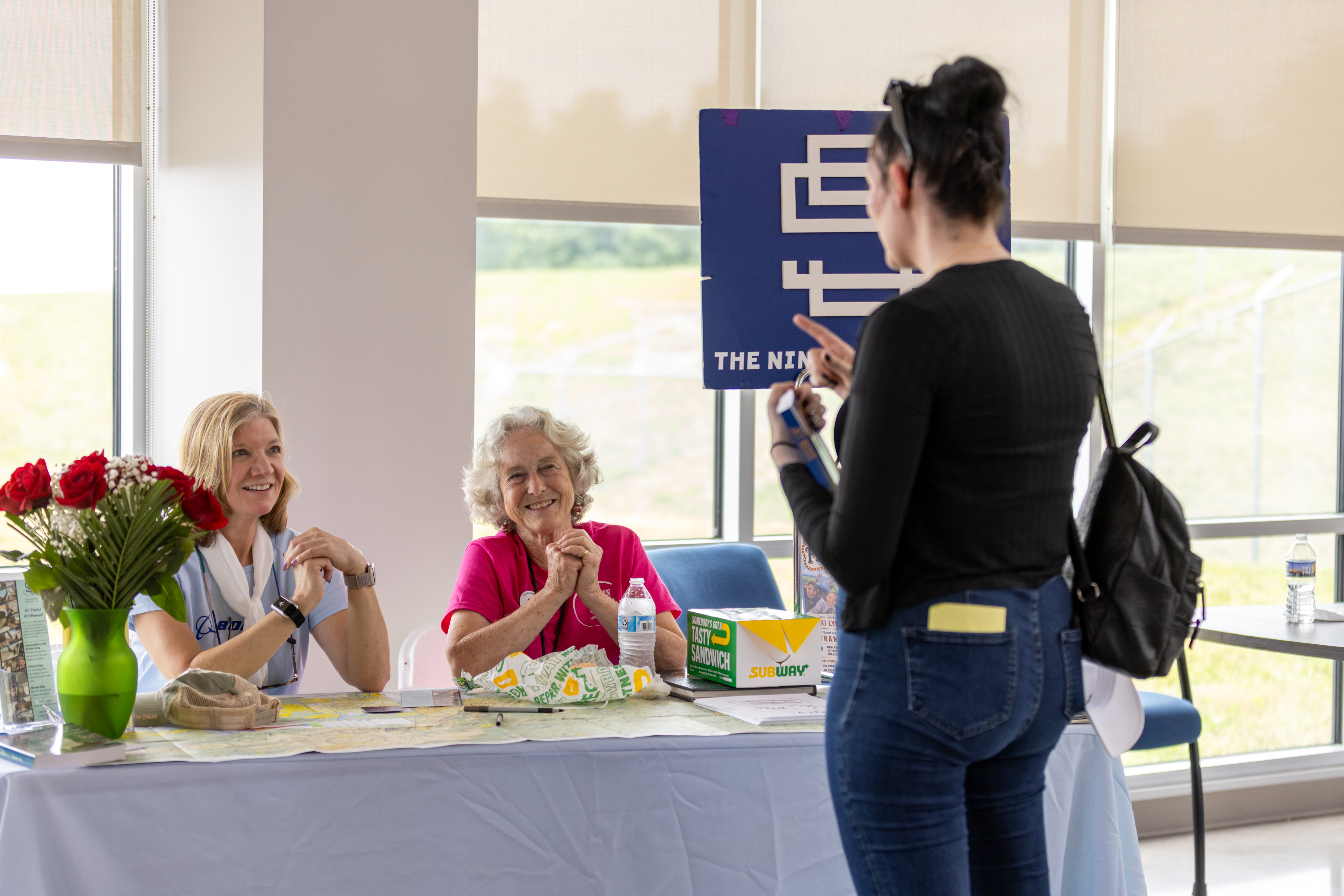 Laura Savino, chairman of the Virgina chapter of The Ninety-Nines, and volunteer Mary McCutcheon speak to attendee Mariah McCloskey in the exhibitor area. Photo by Rebecca Boone.