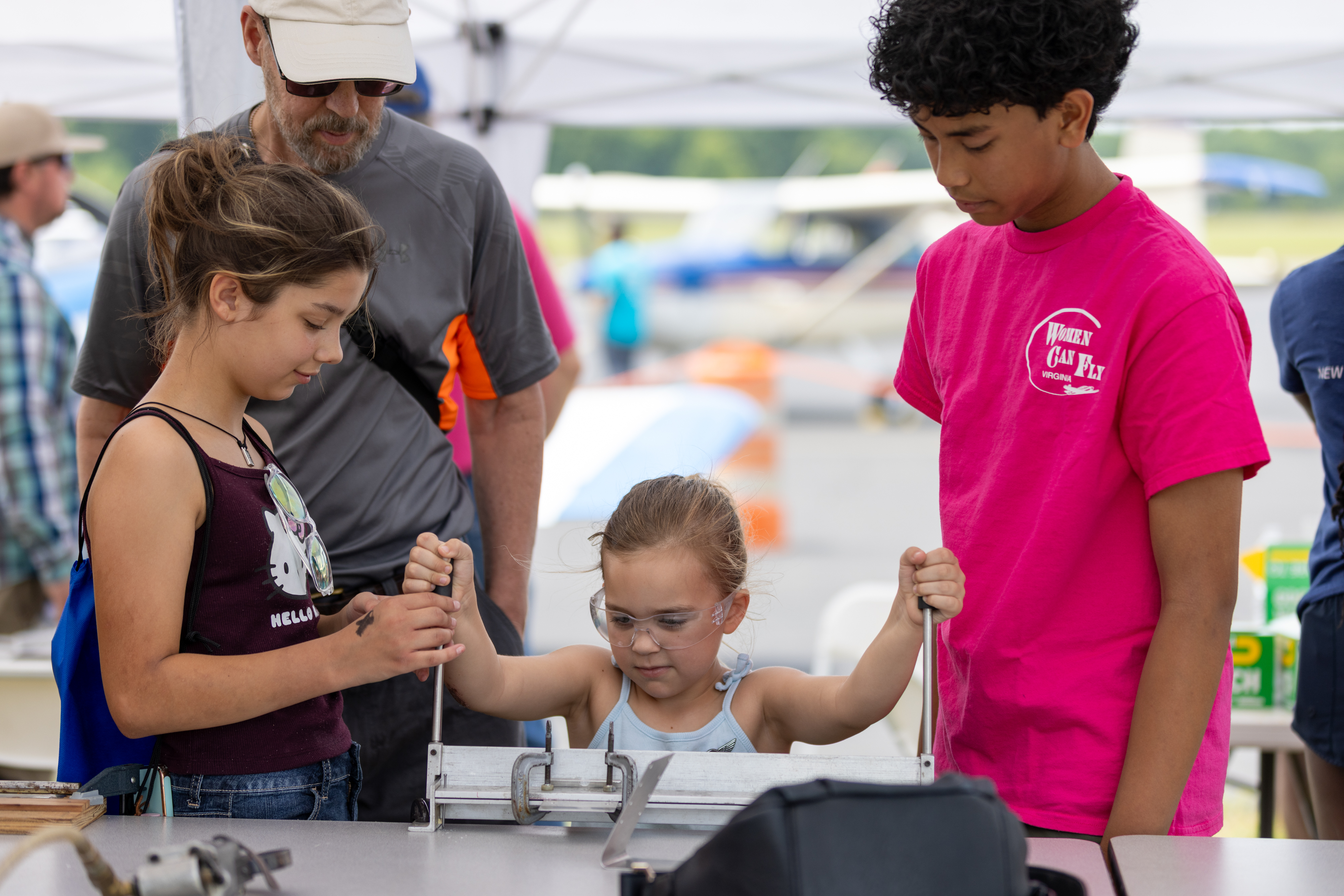 A young attendee crafts a phone stand out of sheet metal at the “Women Can Build” tent. Photo by Rebecca Boone.