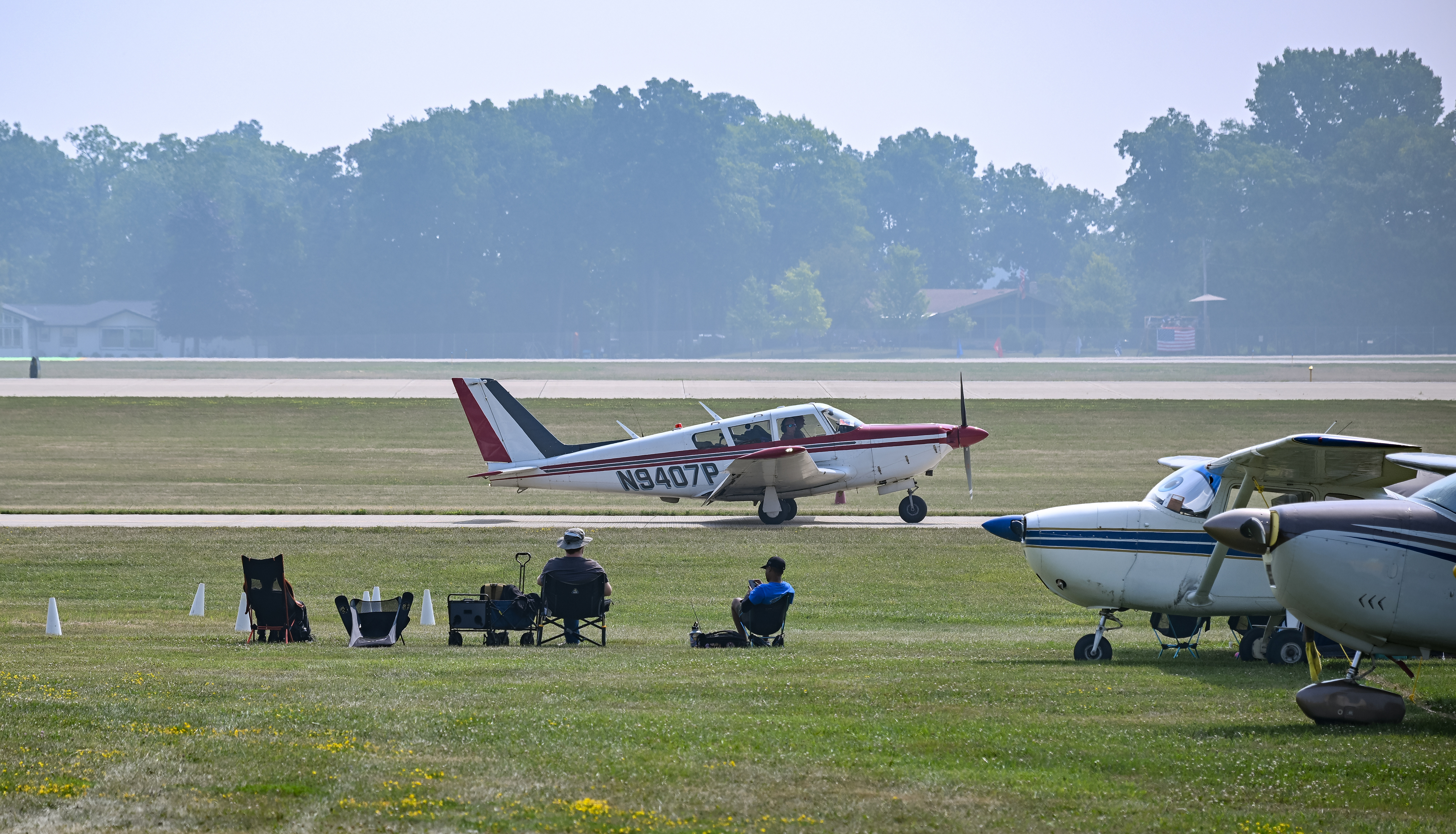 A 1969 Piper Comanche 260 taxis past onlookers after landing in haze caused by Canadian wildfires. Photo by David Tulis.