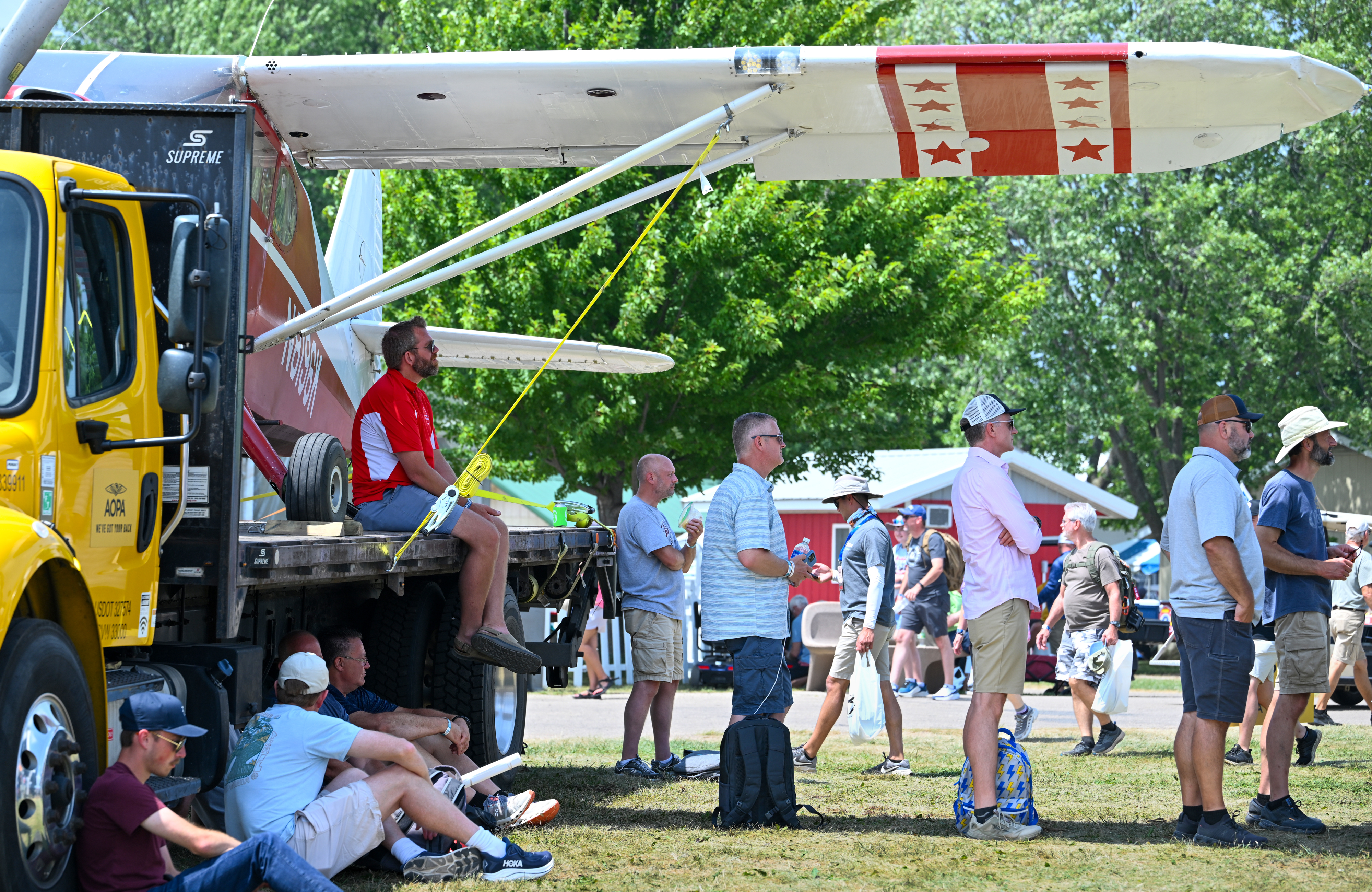 Attendees relax under the wing of Minnesota pilot Darrin Smedsmo’s Stinson on the AOPA campus. Gratitude for AOPA's help recovering the airplane from a tribal reservation impound lot where it was held for months after an emergency landing moved Smedsmo to bring the airplane to Oshkosh for display. Photo by David Tulis.