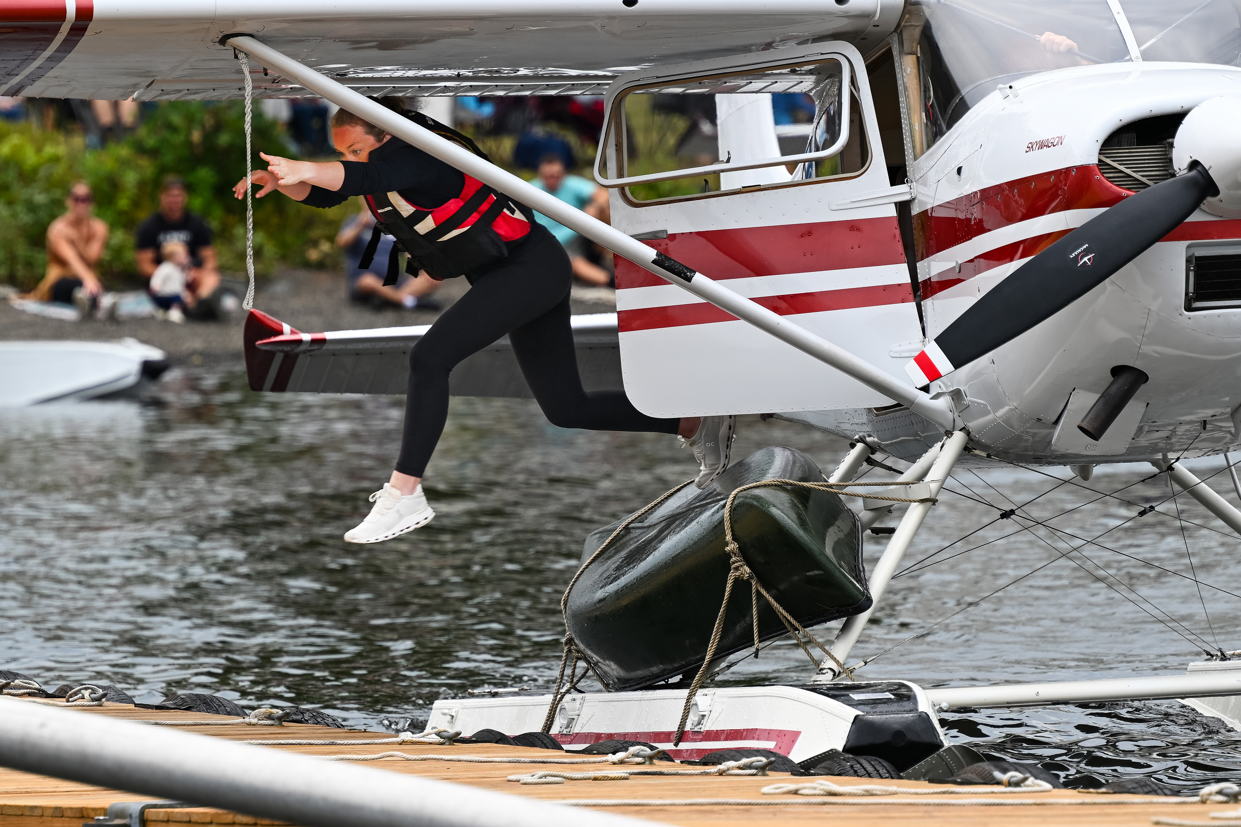 Baily Cust launches herself from her uncle’s 1969 Cessna 180 floatplane to untie a canoe lashed to its strut and complete the competition. Photo by David Tulis.
