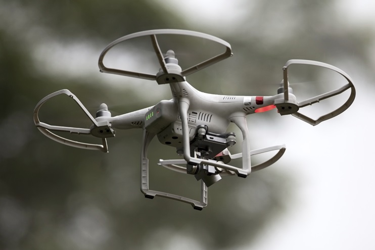 A small, remotely controlled DJI Phantom drone with a built-in camera hovers in the sky. iStock Photo.                                                                                                                               