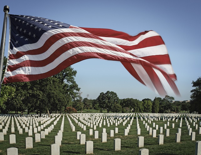 A U.S. flag flies over gravestone markers at Arlington National Cemetery. iStock photo.                       