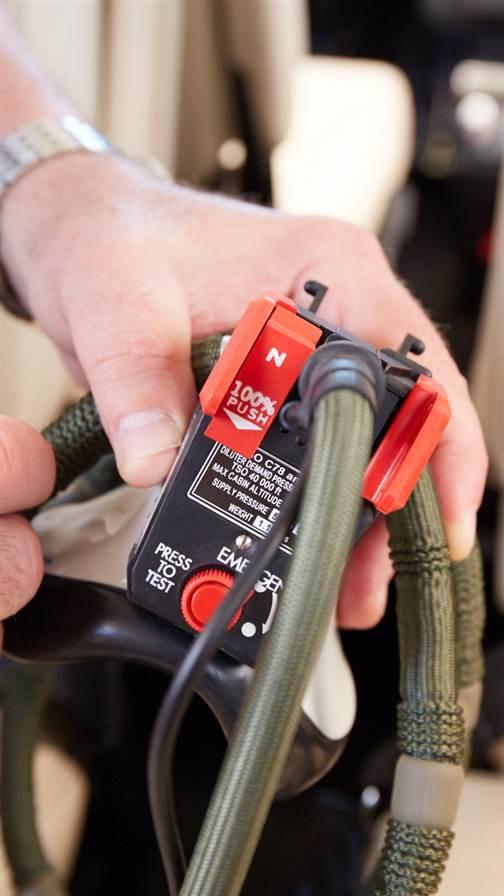 Newer masks have a panel switch for normal and 100-percent modes. The round red button selects emergency mode.