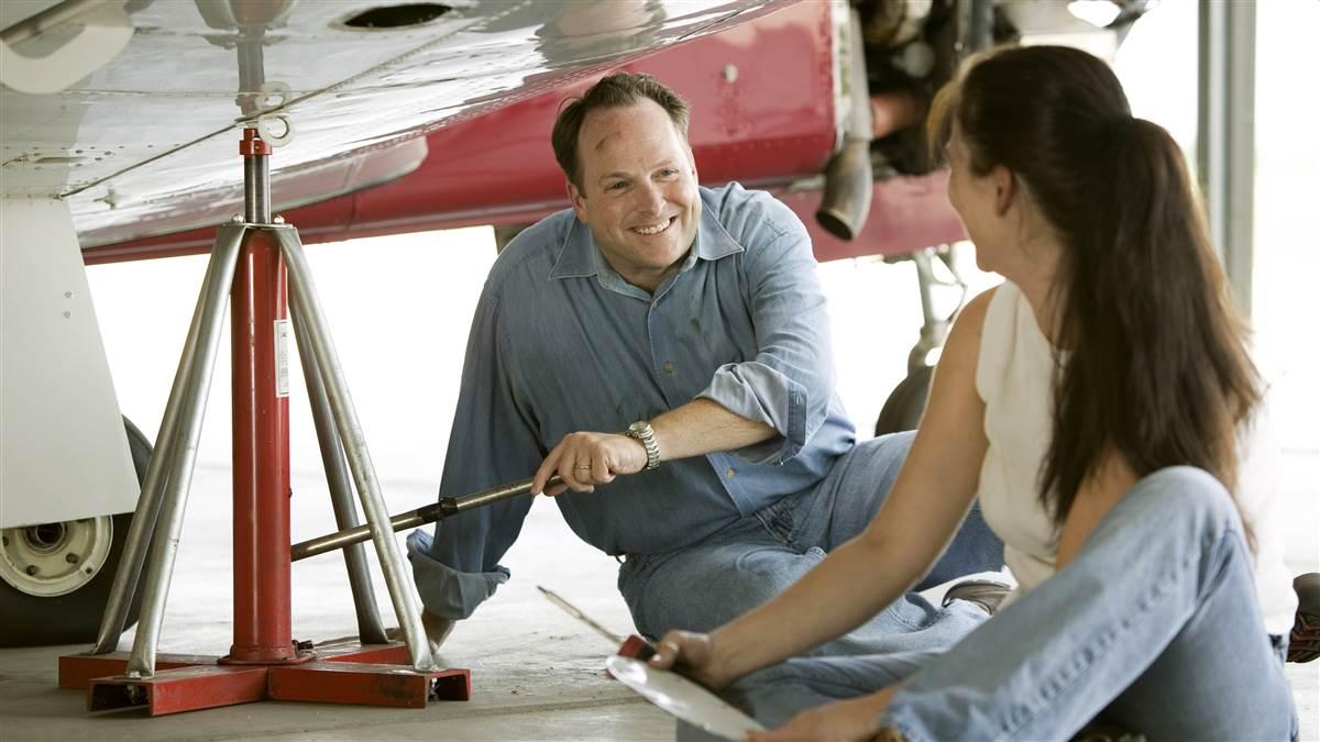 A husband and wife under the wing of their aircraft assisting the mechanic for their first annual inspection..Wichita,  KS  USAhttp://mikefizer.comImage #: 04-377_091.tif