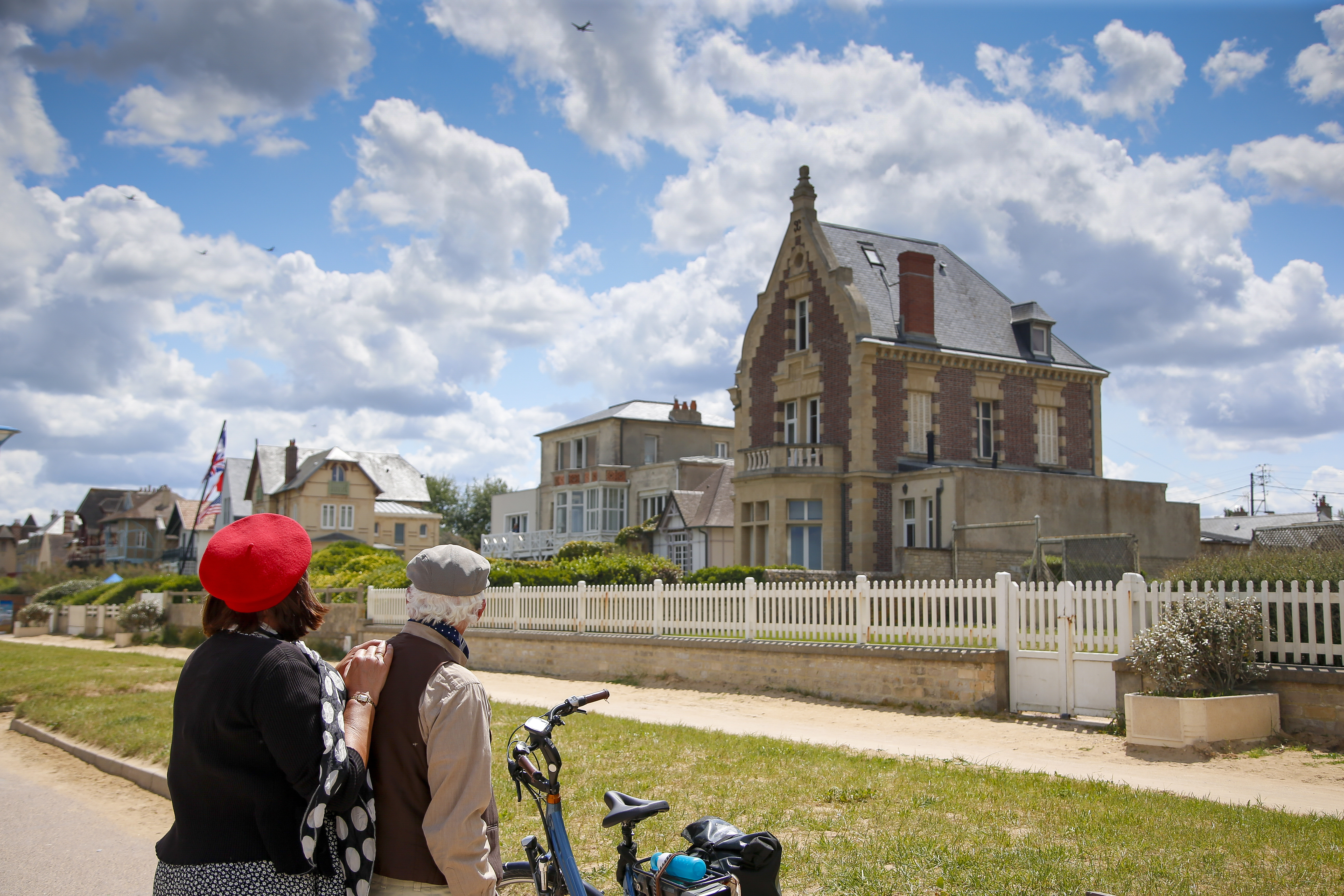 French citizens pause to watch the transports fly over their community in Normandy.