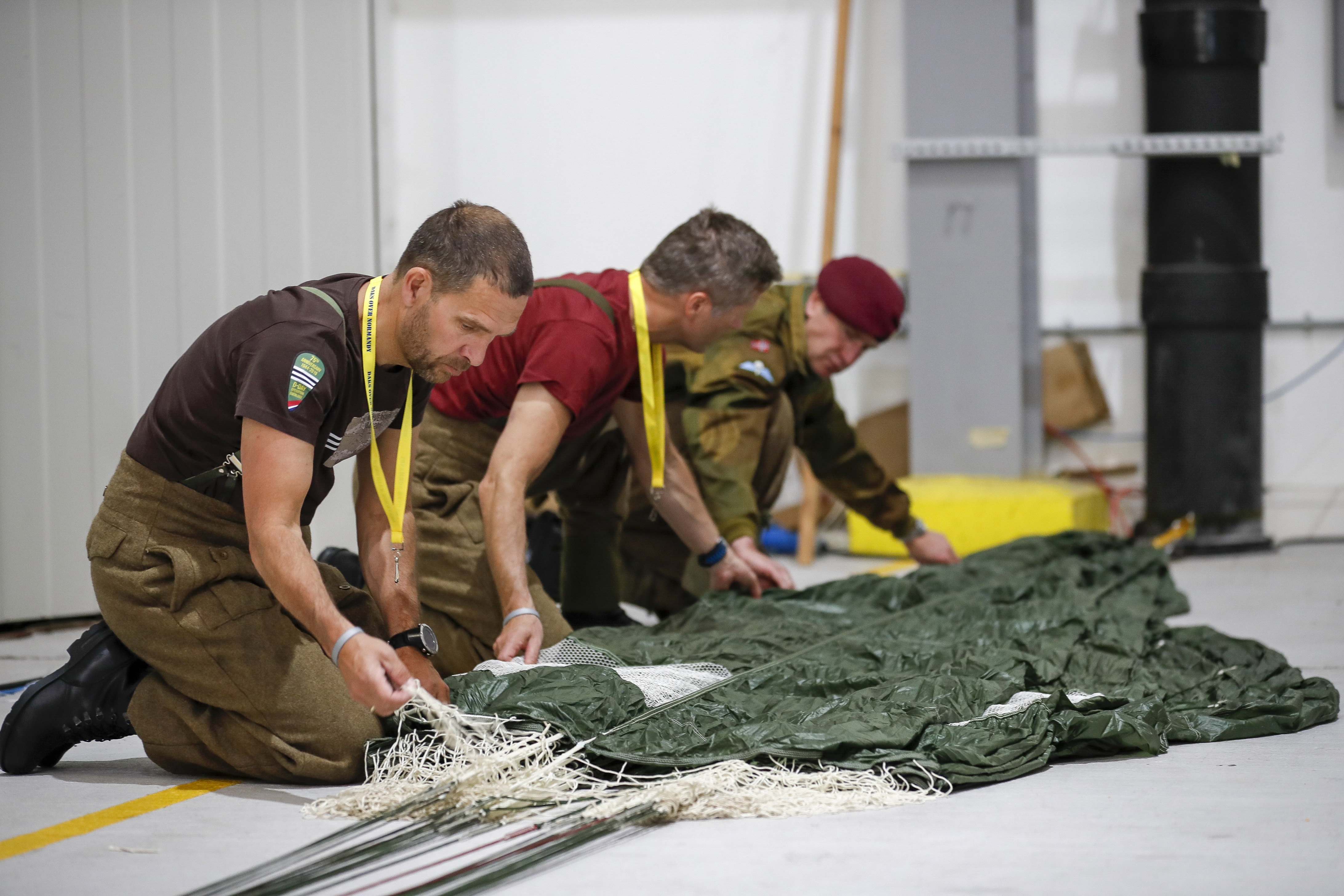 Parachutists carefully pack their chutes after a practice jump in England.