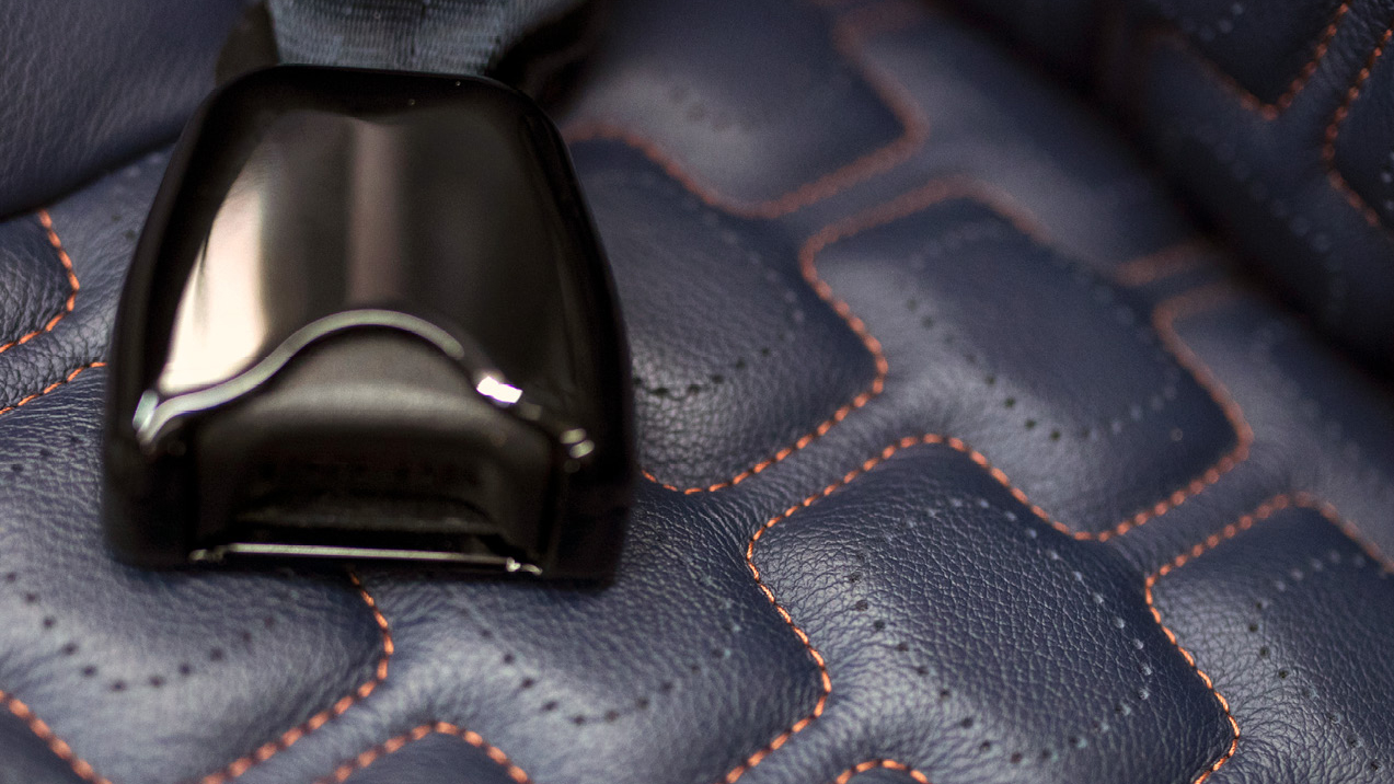 A detail from the seat upholstery shows accent stitching.
