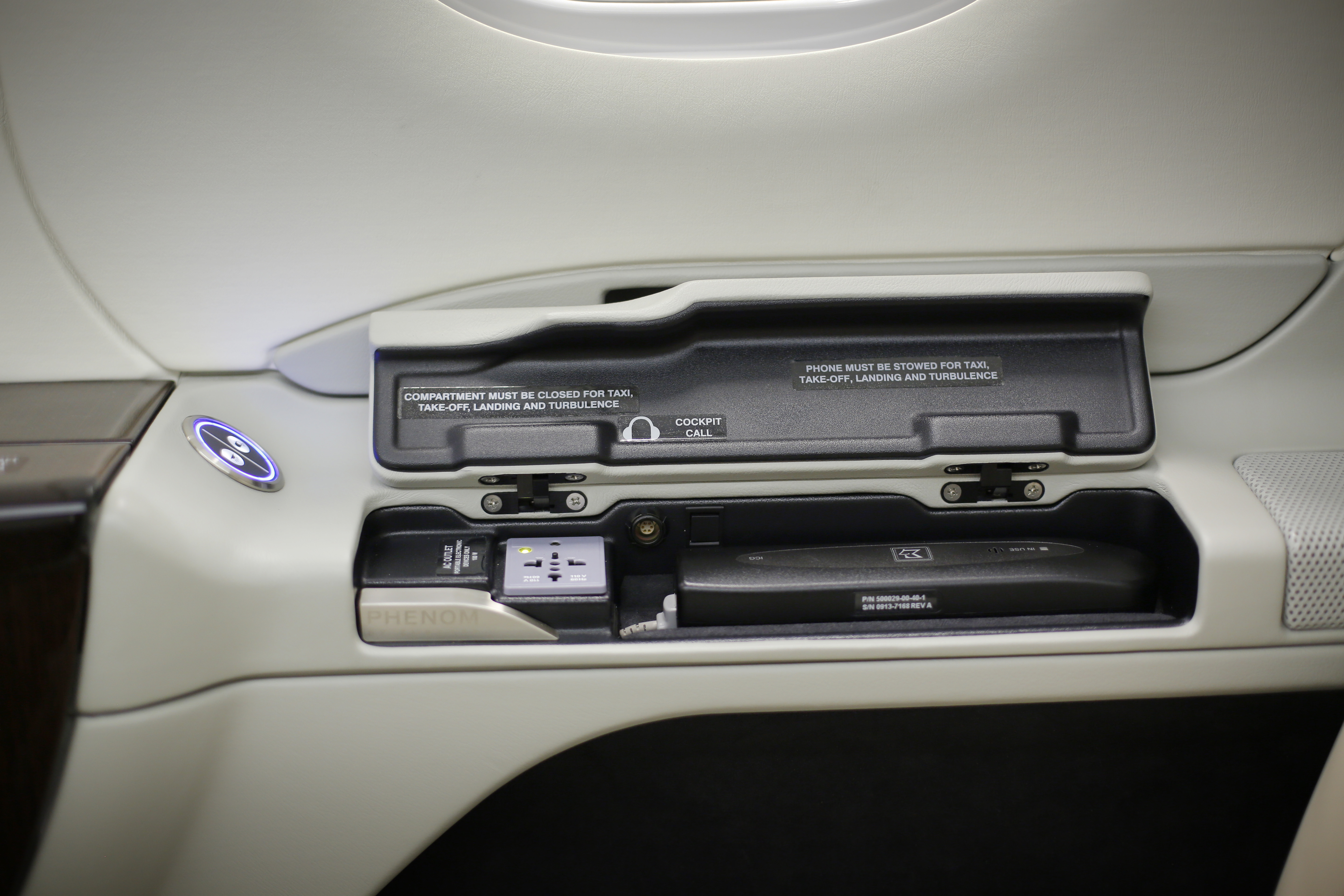 Embraer Lineage 1000E: Cabin controls, power outlets, and satphones are mounted on a side ledge next  to to a “principal” seat (sometimes called the “boss’s” seat) of an Embraer Lineage 1000E. 