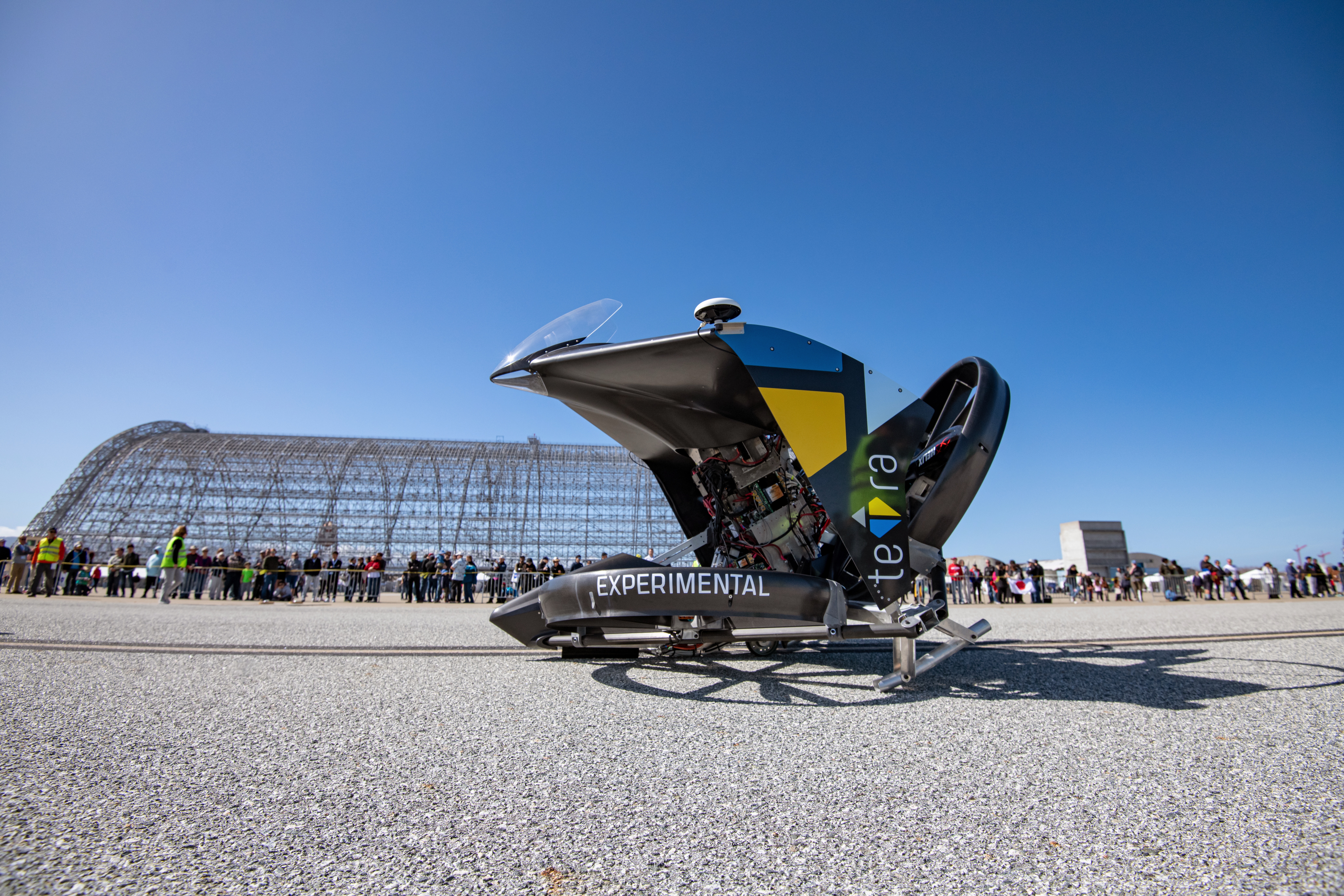The futuristic teTra 3, from Japan’s Team teTra, is displayed in front of an airship hangar’s framework.
