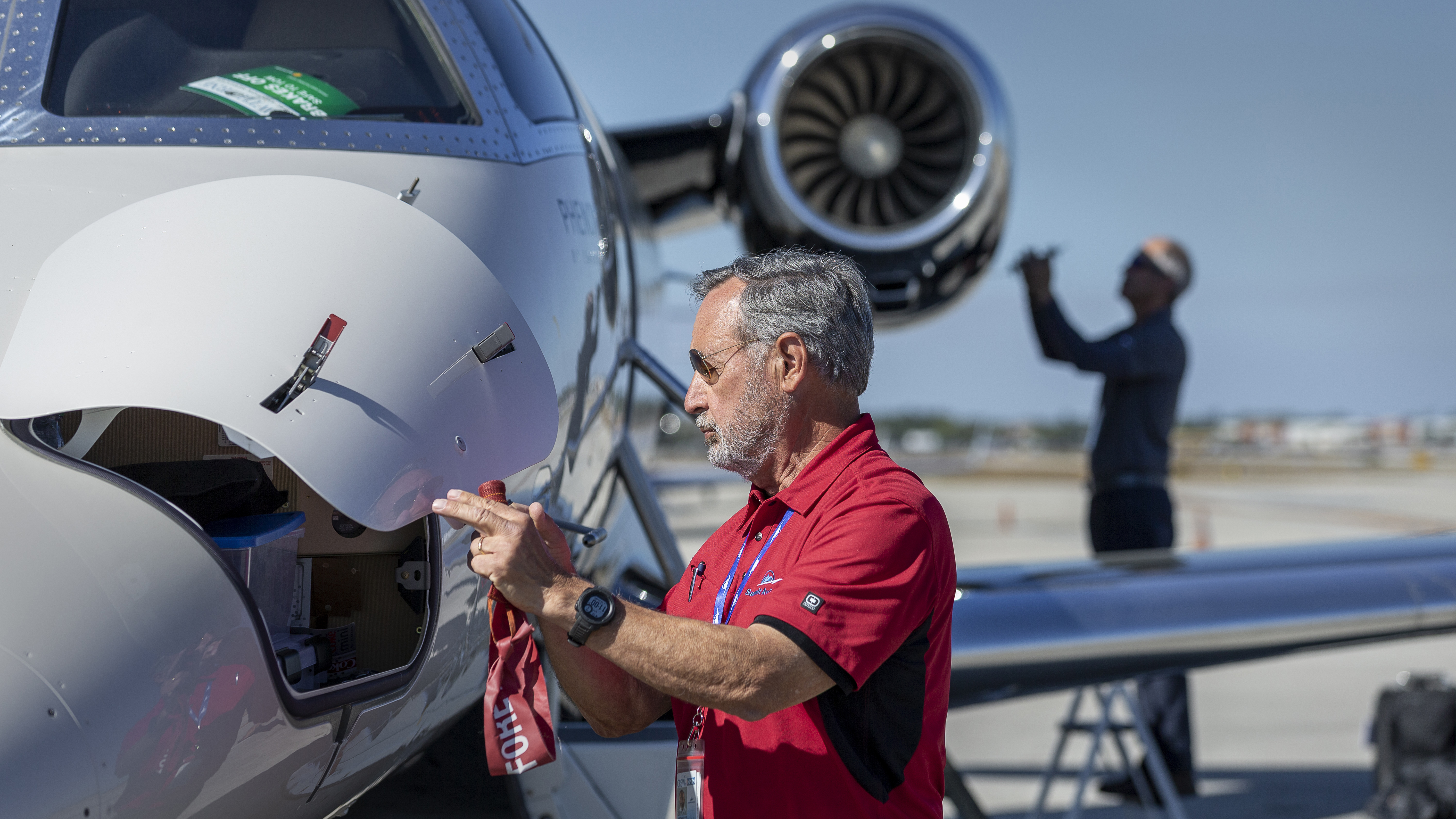 Summit Aviation’s Paul Proffett (foreground) and Howley (background, checking engine oil level) during a preflight inspection.