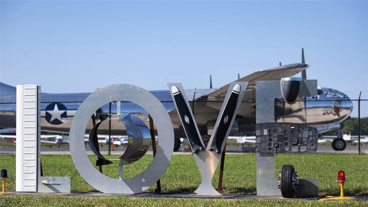 A sign made from aircraft parts at a northern Virginia airfield frames Boeing B-29 Superfortress ‚ÄòDoc‚Äô during preparation for the September 25, 2020, Arsenal of Democracy flyover of Washington, D.C., to recognize the 75th anniversary of Victory in Europe Day. AOPA Photo by David Tulis.