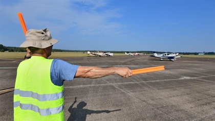 Volunteer Carlos Orellana of Lakeland, Fla., marshals an aircraft to parking at AOPA's Tullahoma Fly-In. He and his wife flew her Cherokee 140 to Tennessee. Photo by Mike Collins.