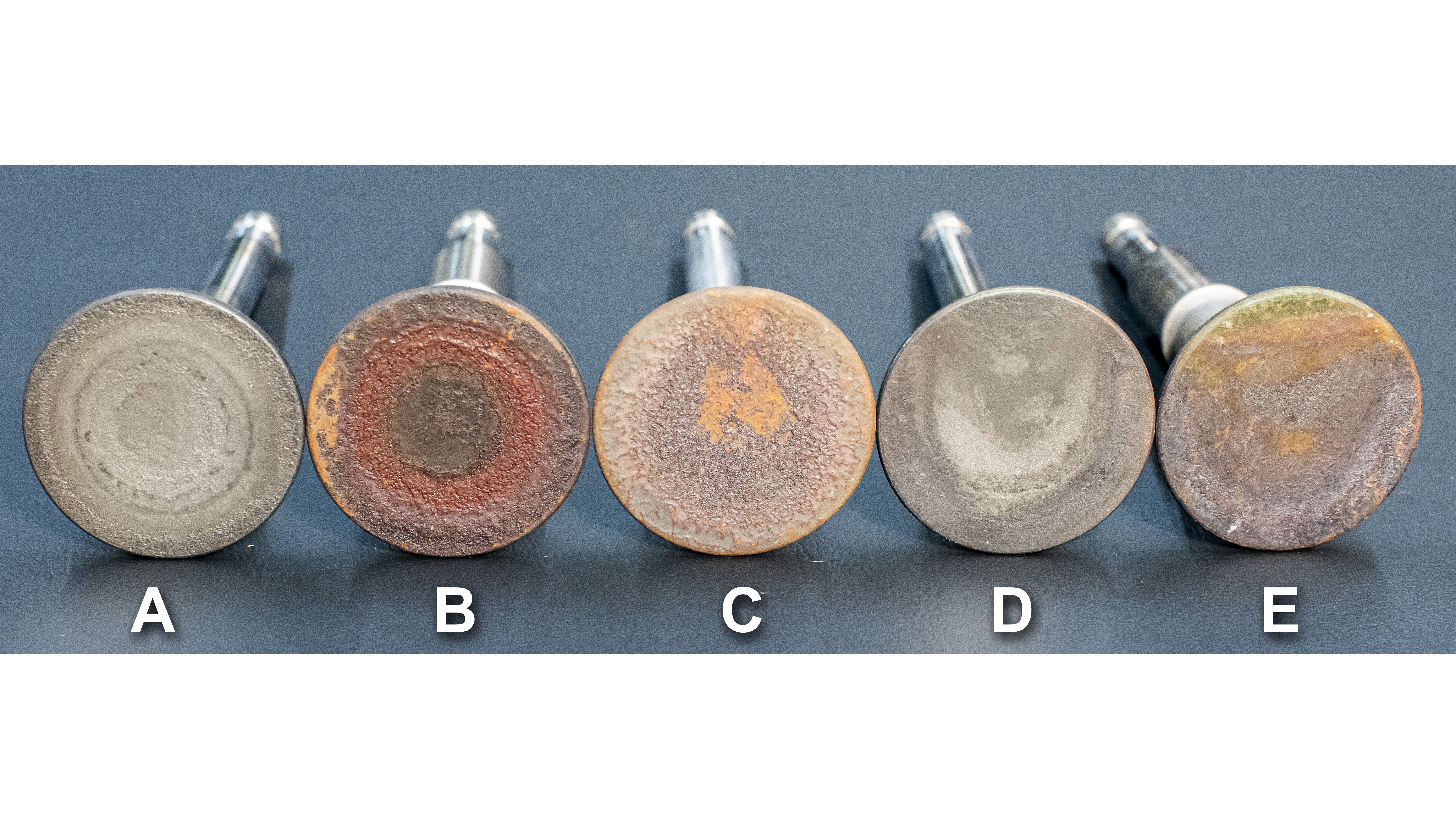 Lineup of five Continental exhaust valves. The left ones look healthy, the right ones don’t.