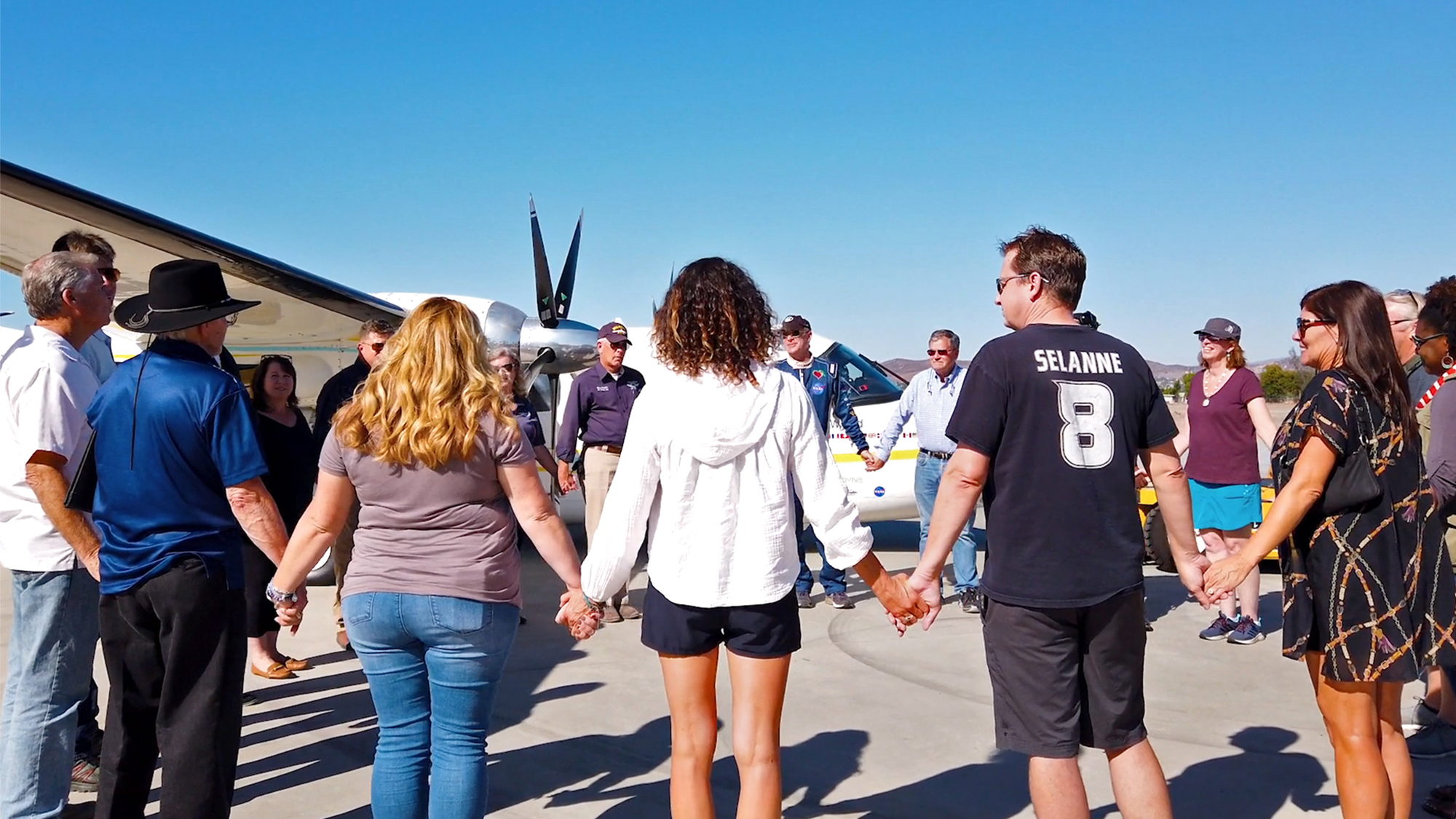 DeLaurentis joins supporters holding hands before he departs from Gillespie Field in San Diego, California, on a polar circumnavigation to spread a message of peace and to highlight general aviation and STEM awareness.